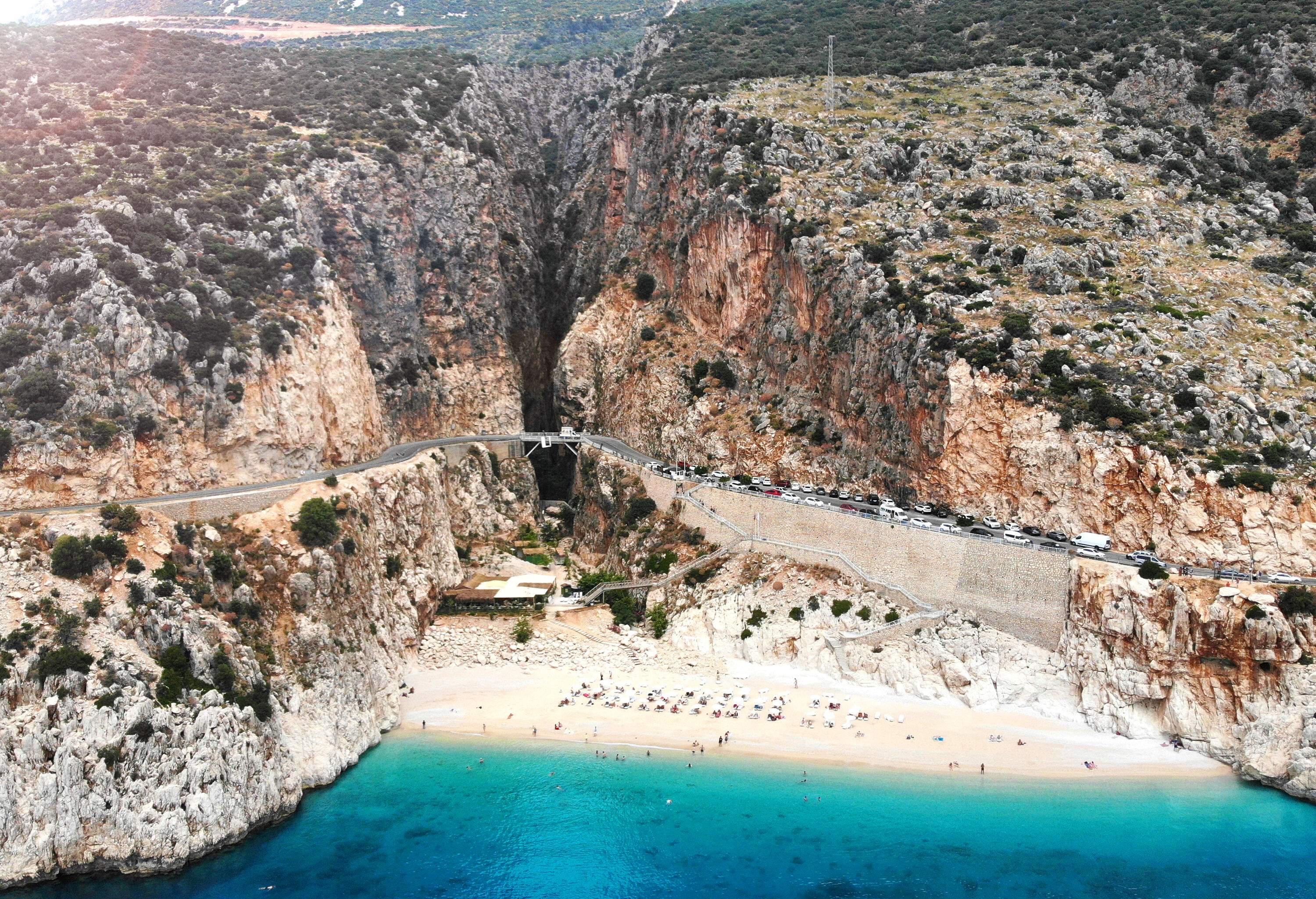 A beautiful bay surrounded by steep cliffs that are bridged by a roadway along the slopes.
