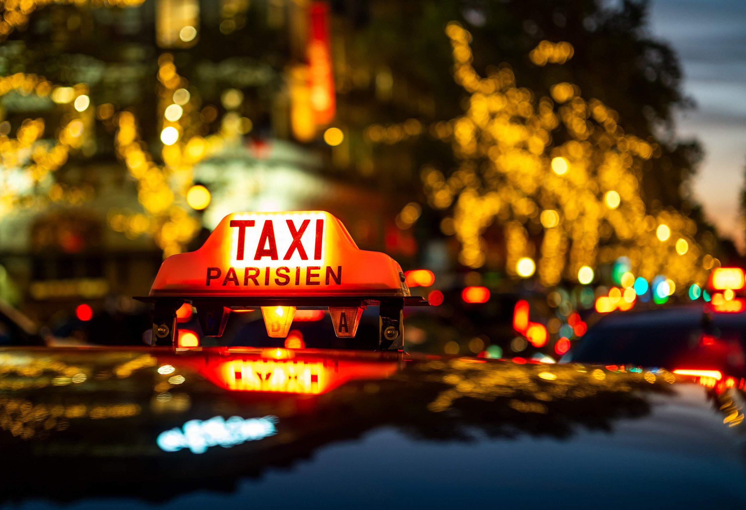 Taxi sign with Paris street at night in background.