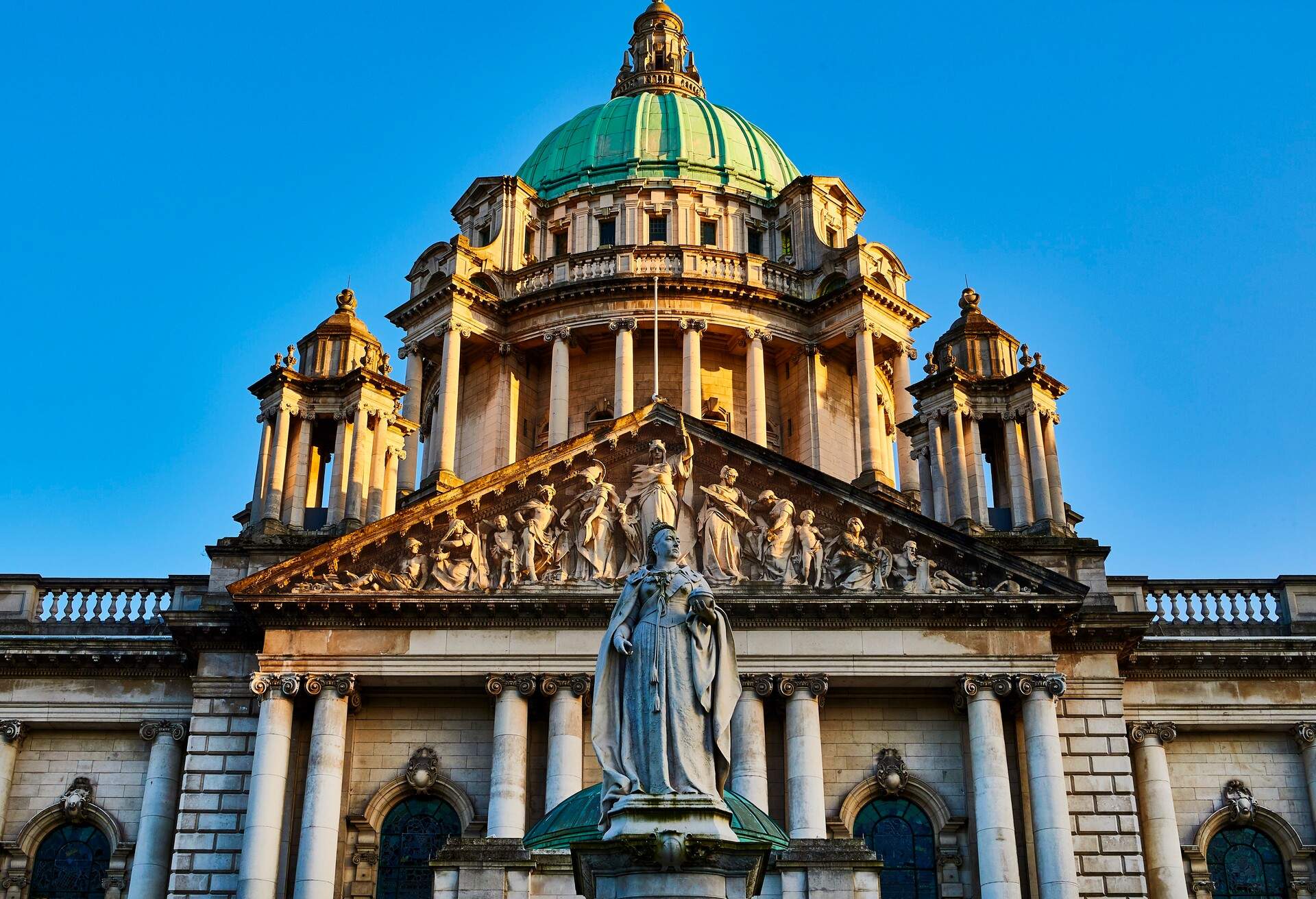 An elegant Baroque Revival civic building adorned with large columns, pediments, statues, sculptures and towers topped with domes.