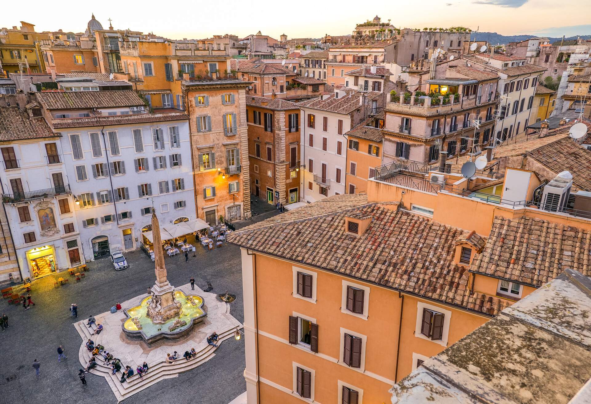 People sitting on the steps around the Fontana del Pantheon platform in the centre of Piazza della Rotonda.