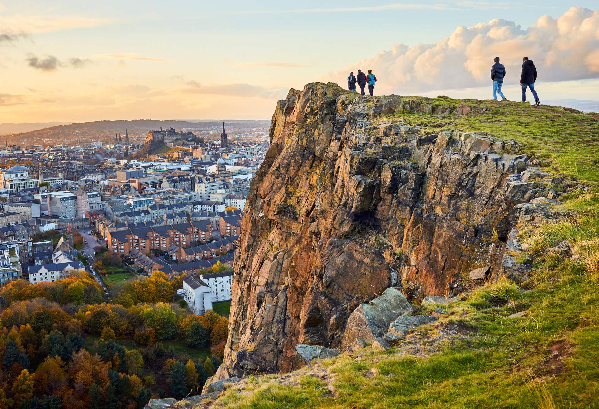 People walking along the headland of a steep cliff with spectacular views of the city below.