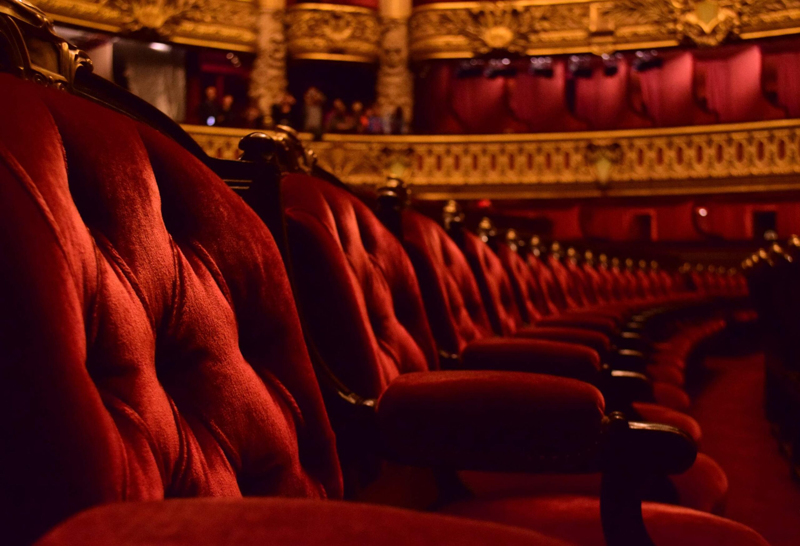 A row of theatre seats, upholstered in rich red fabric.