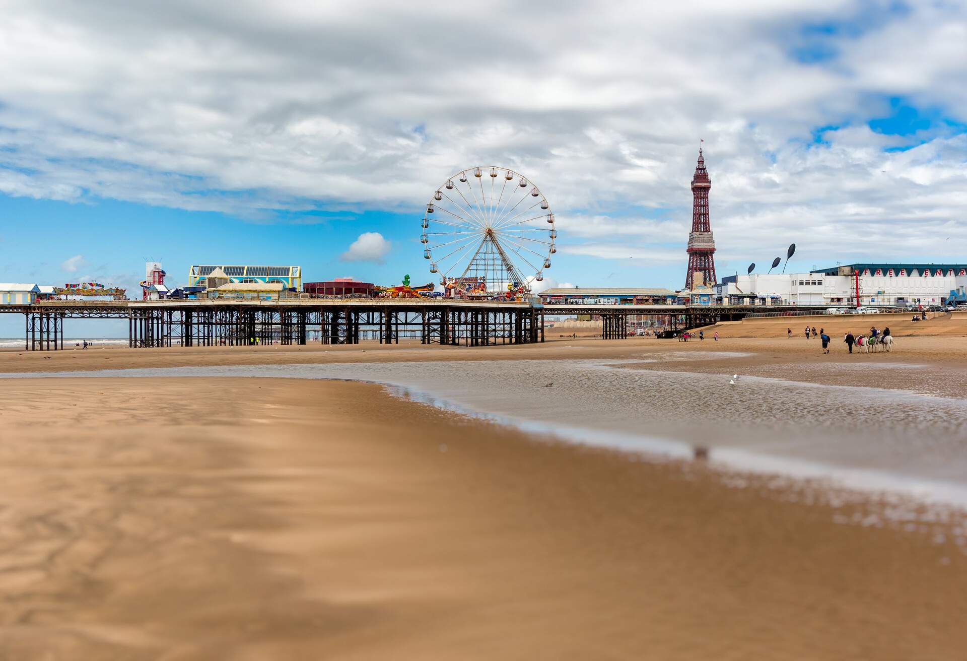 The landscape of Central Pier with an amusement park and Ferris wheel at low tide in summer.