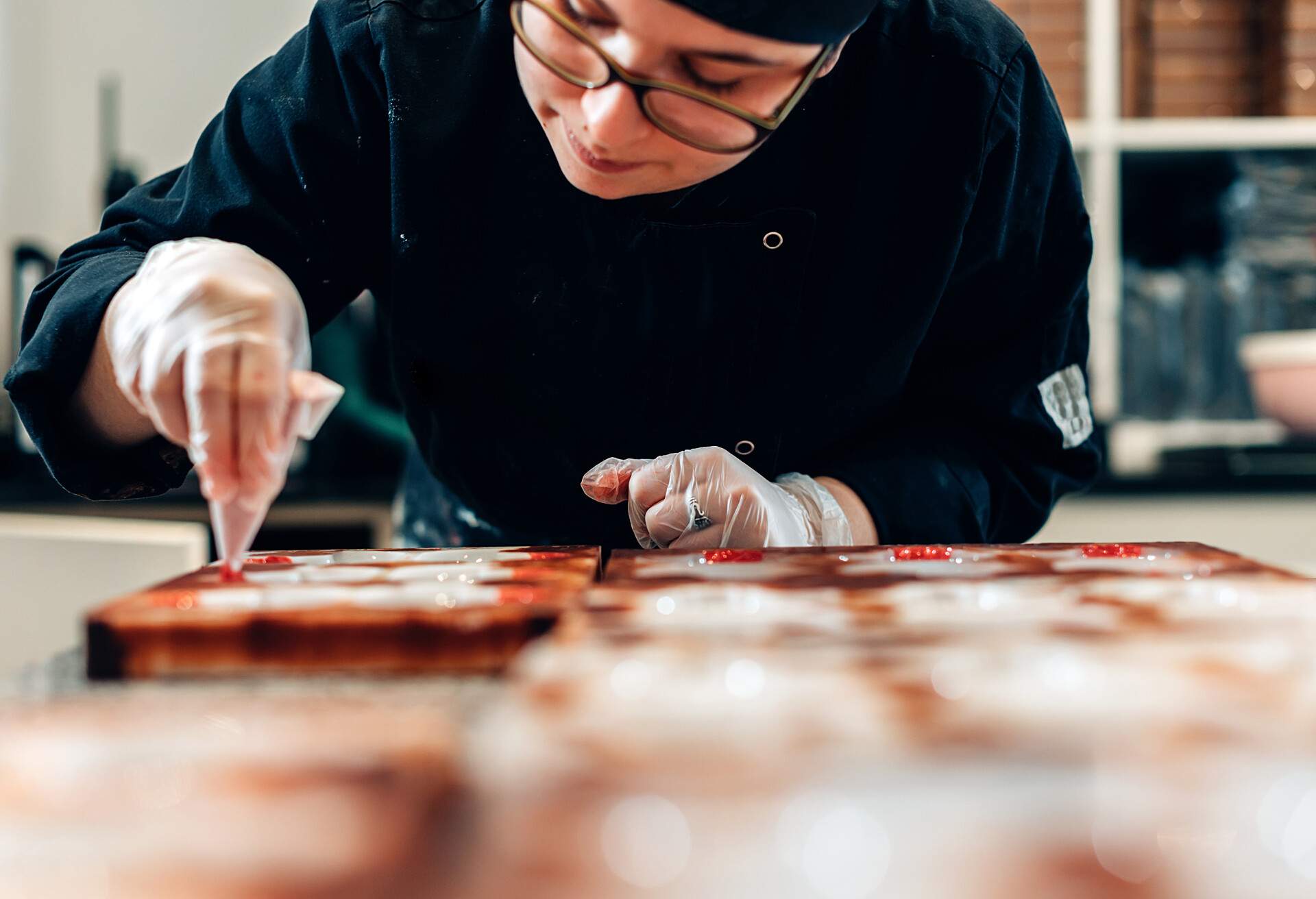 A chef using a piping bag to fill moulds.