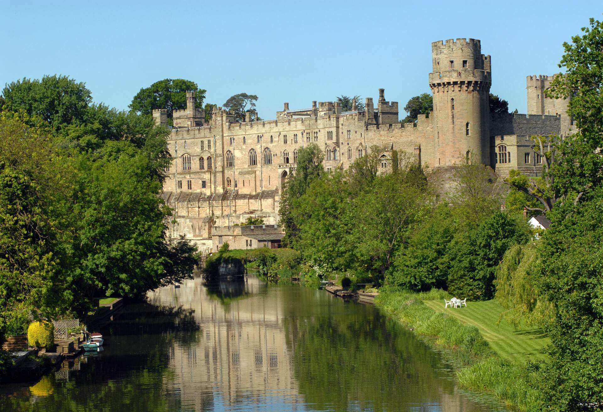 An old medieval castle with a visible round tower along the lush green river.