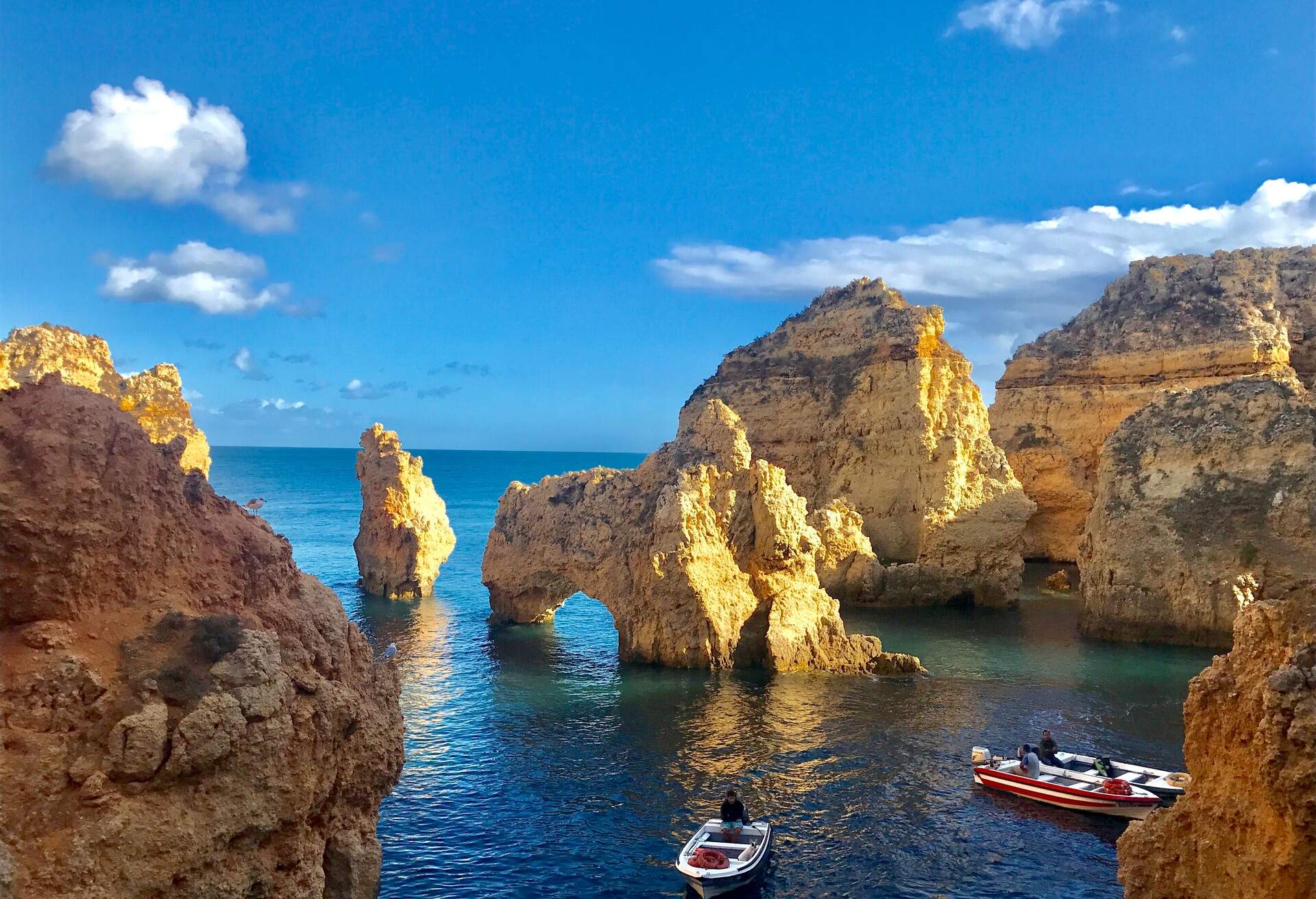 Boats floating among the unique rock formations scattered across the sea.