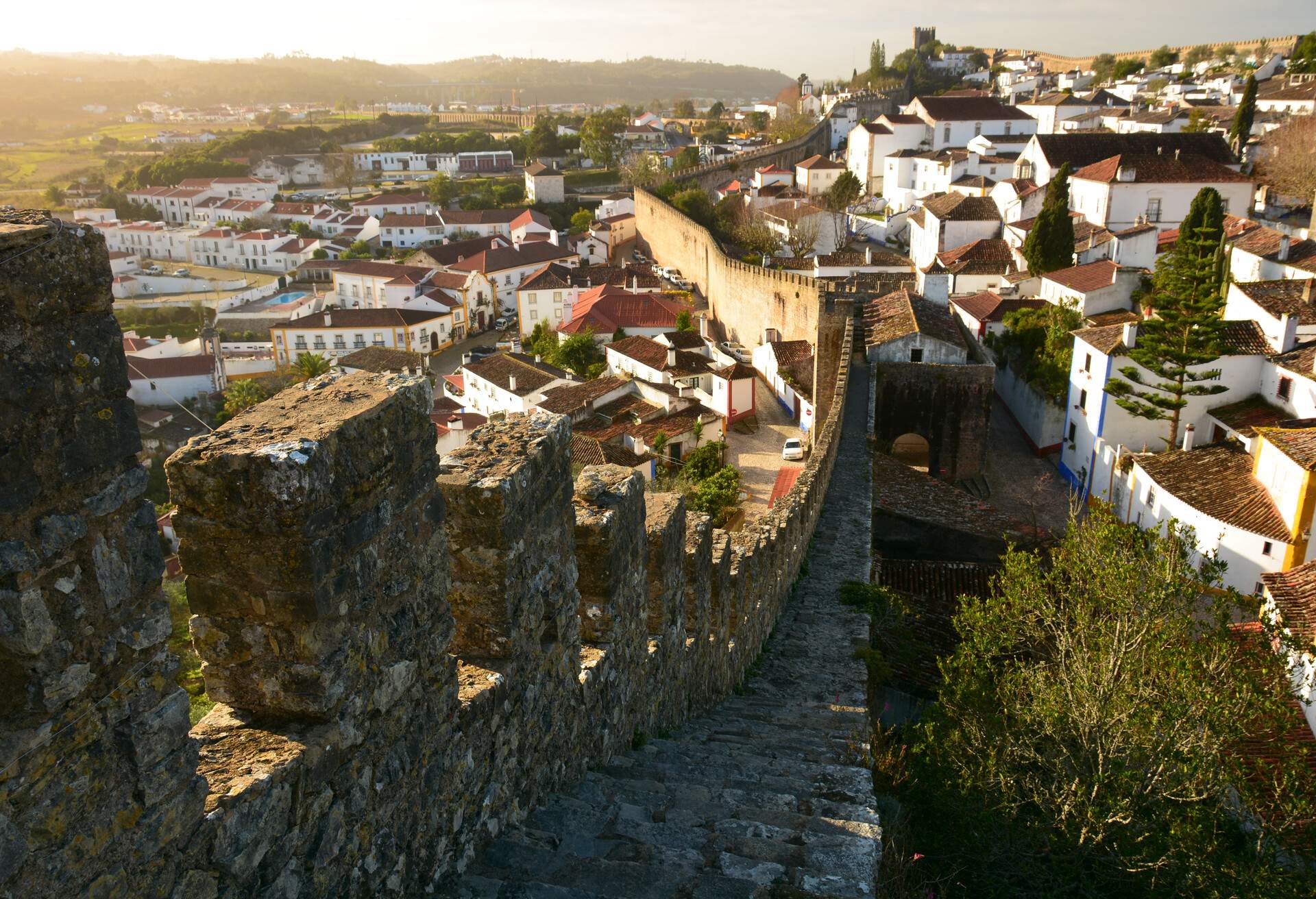 The sun rising over the walled city of Obidos. Guard towers can be seen in the distance.