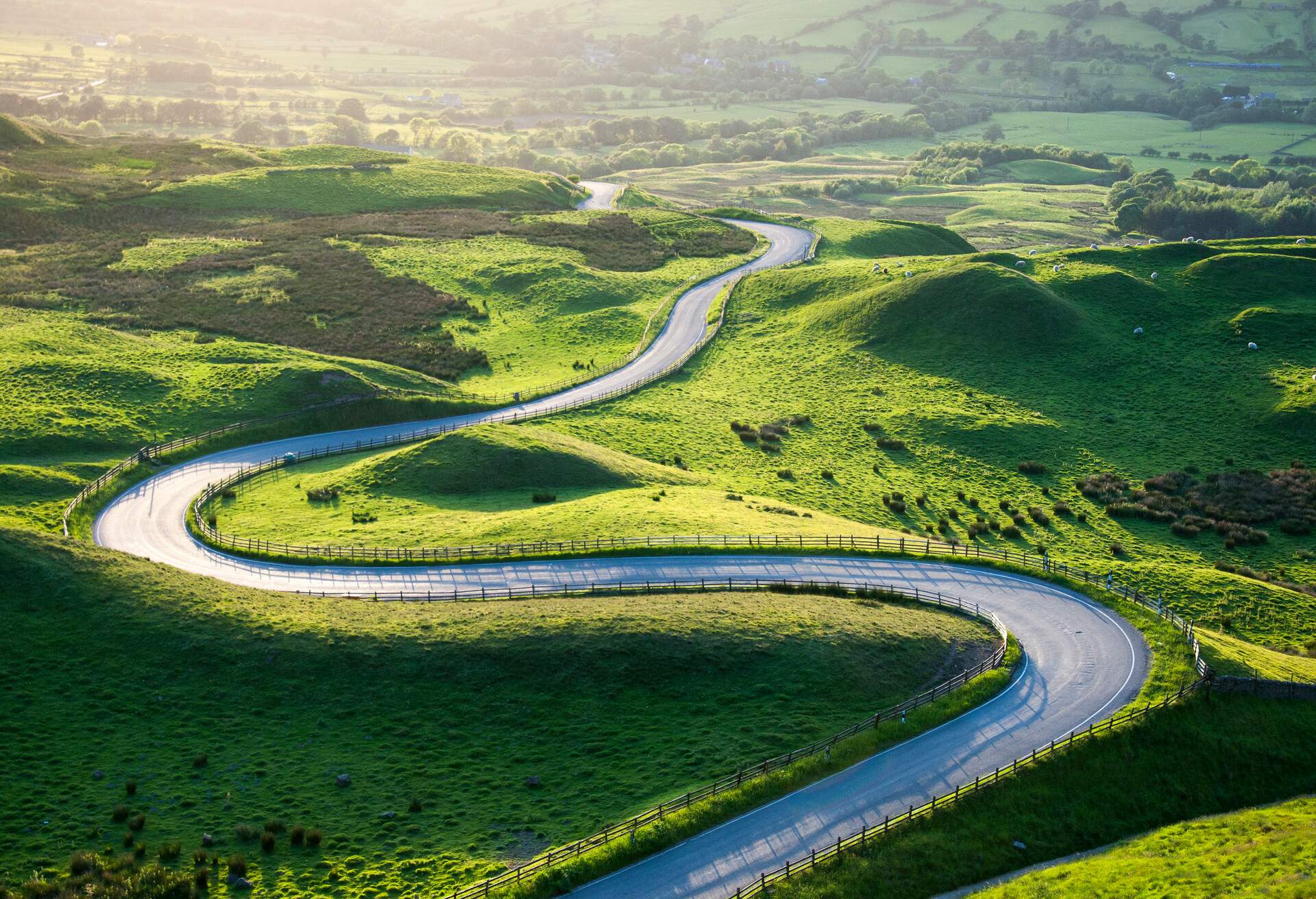 A winding road across the rolling hills covered in grass.