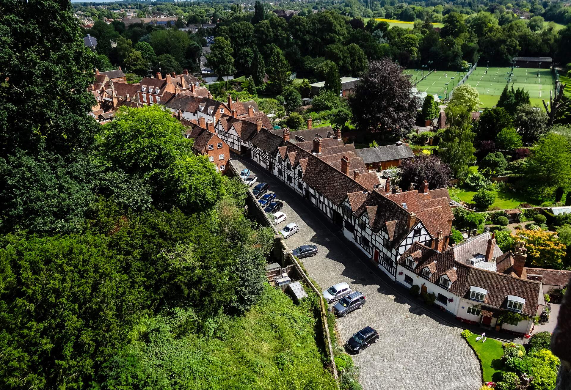 Cars parked along the side of a road lined with timber-framed buildings.