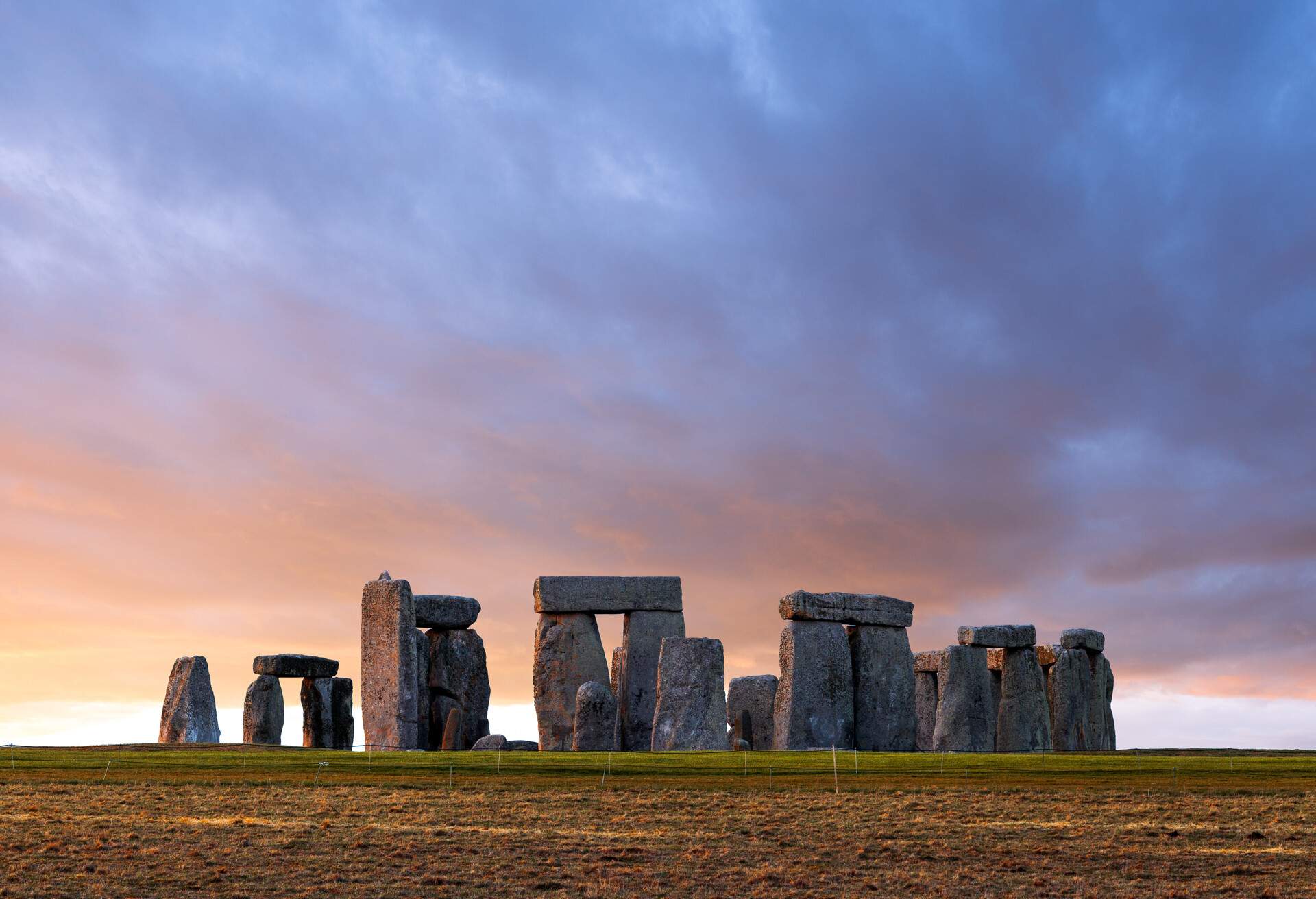 The iconic Stonehenge, a circle of enormous stones arranged like a doorway over a grassy field.