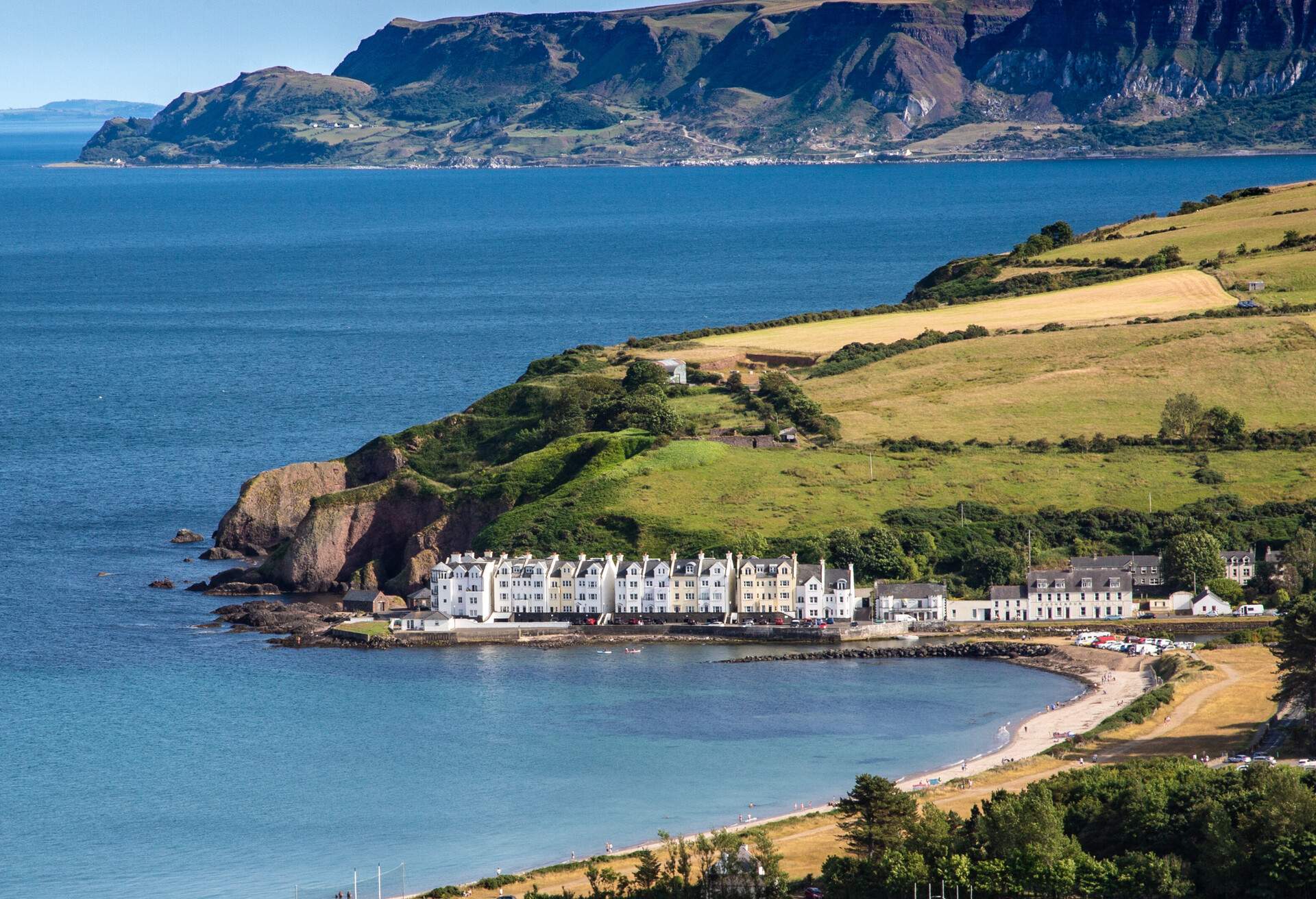 A row of white houses on the shore next to the beach in Cushendun in Northern Ireland