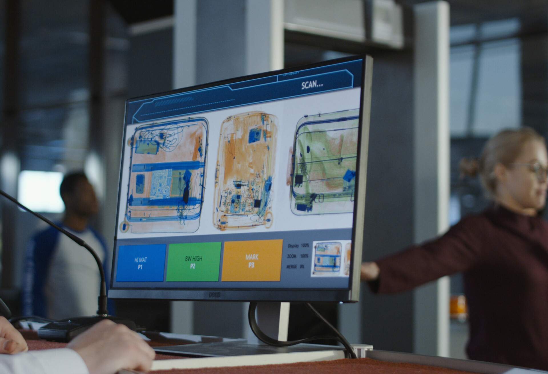 An anonymous man at an airport checkpoint carefully examines luggage on the X-ray screen for security purposes.