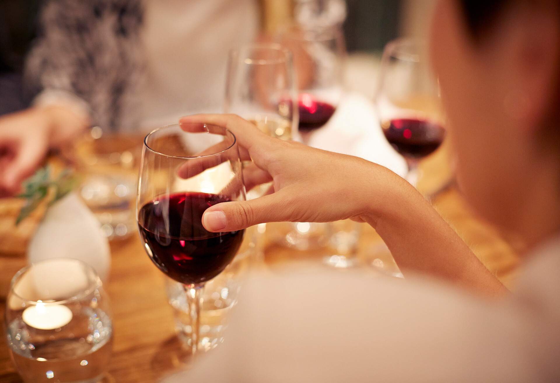 A person holds a wine glass while others rest on a table.