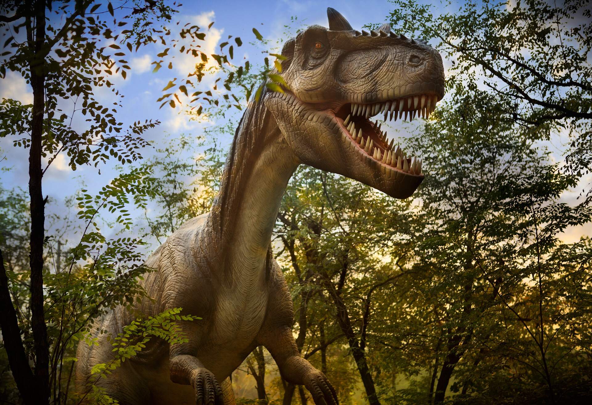 A realistic replica of a dinosaur surrounded by tall trees.