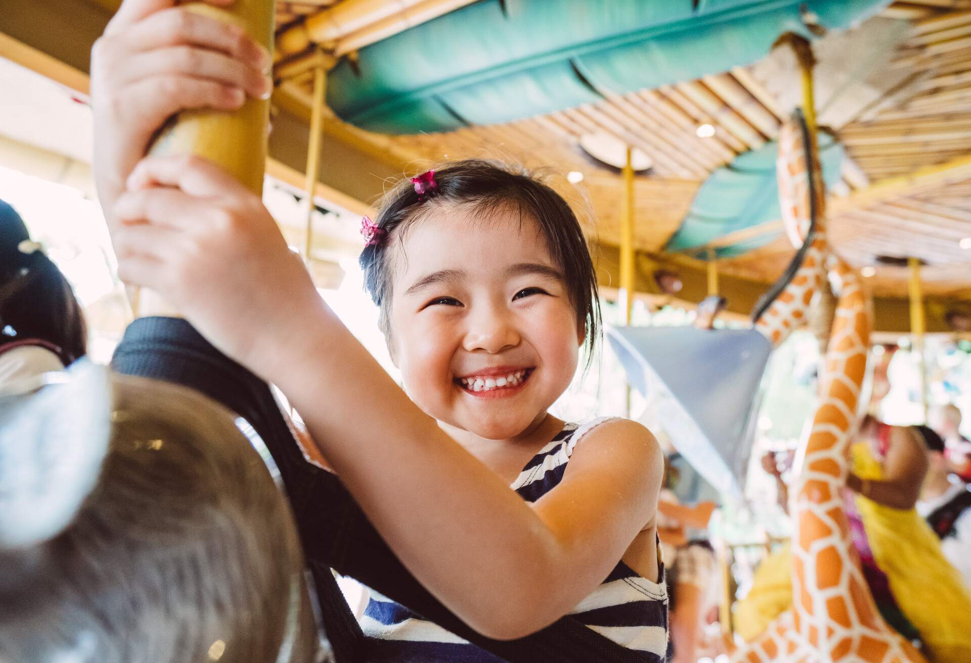 A joyful little girl rides on a carousel.