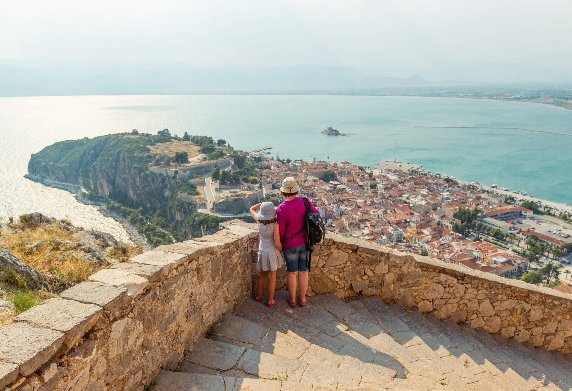 Mother and daughter admiring aerial view of Nafplio city from the fortress. Greece.