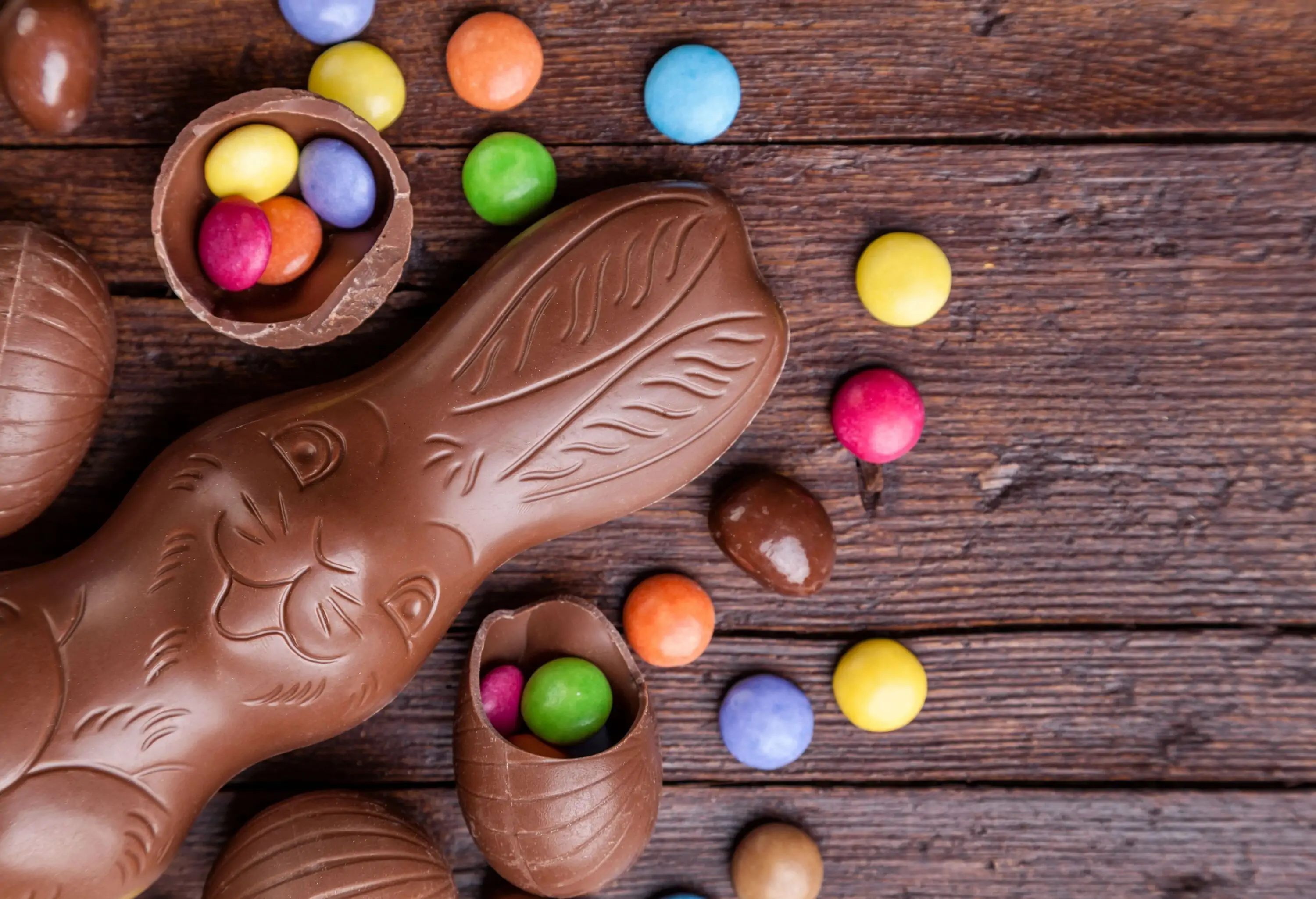 A chocolate shaped like a rabbit and cracked chocolate eggs with colourful circle candies.