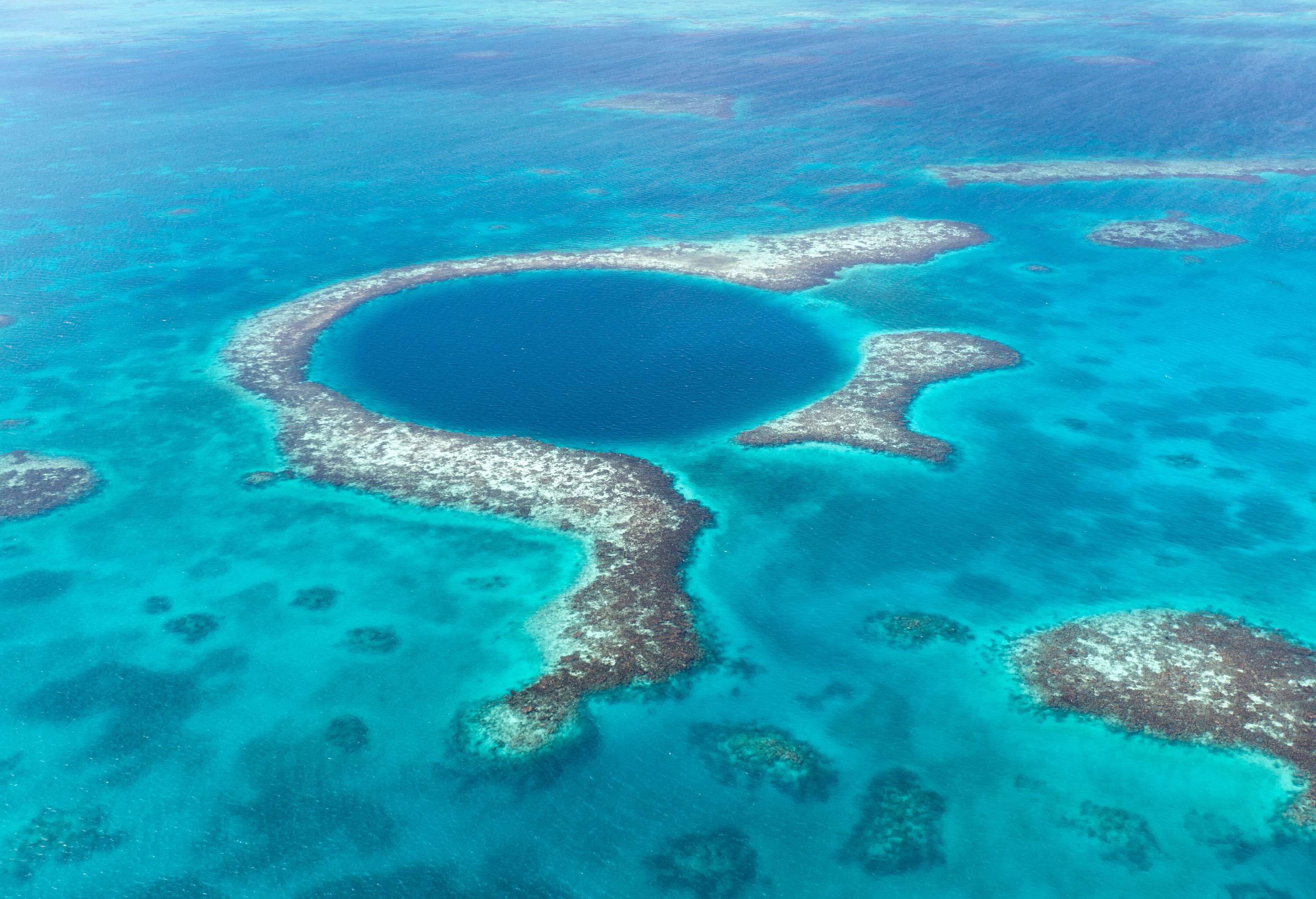 A coral reef surrounds a deep circular sinkhole.