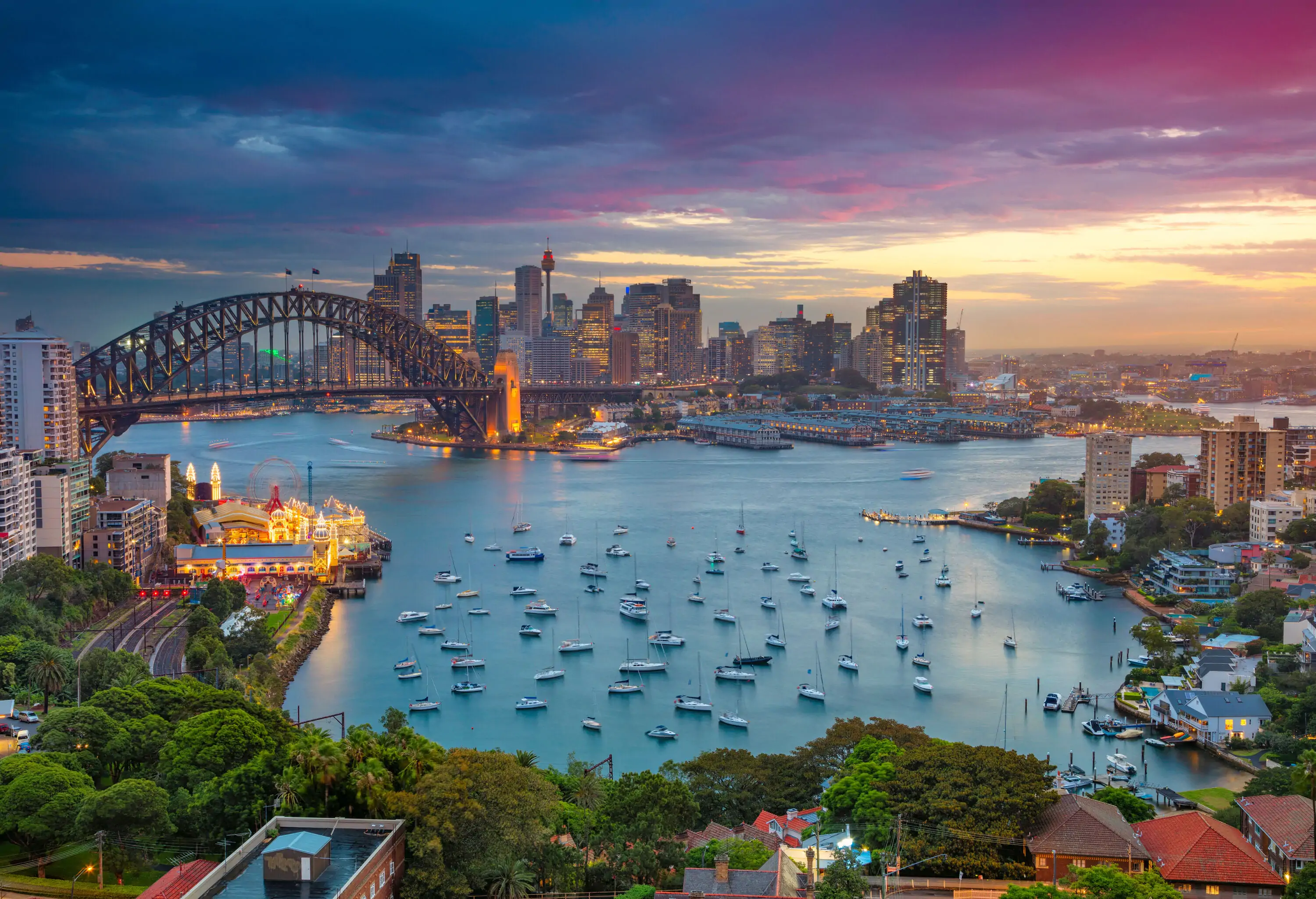 Cityscape image of Sydney, Australia with Harbour Bridge and Sydney skyline during sunset.