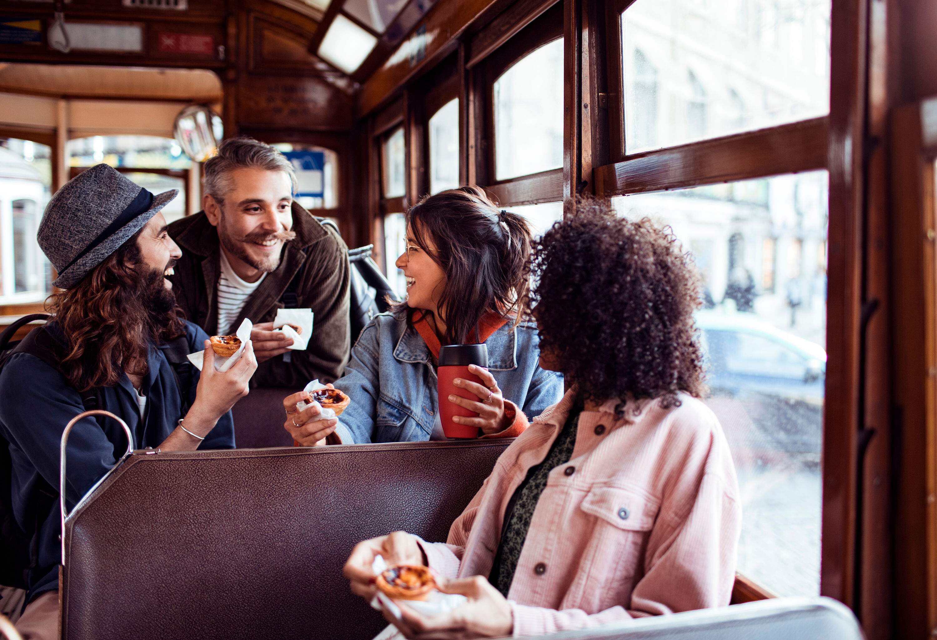 A cheerful group of friends shared laughter inside a tram, exchanging smiles while holding delicious tarts.
