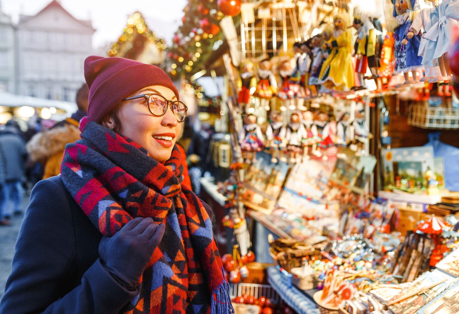 Cheerful woman in warm clothes and scarf gaze at the variety of colourful Christmas souvenirs on display.
