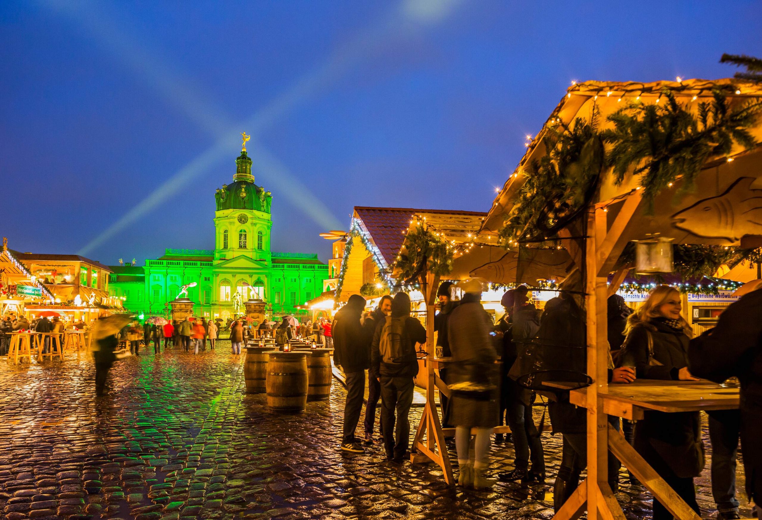 a christmas market in Berlin with a castle in the background