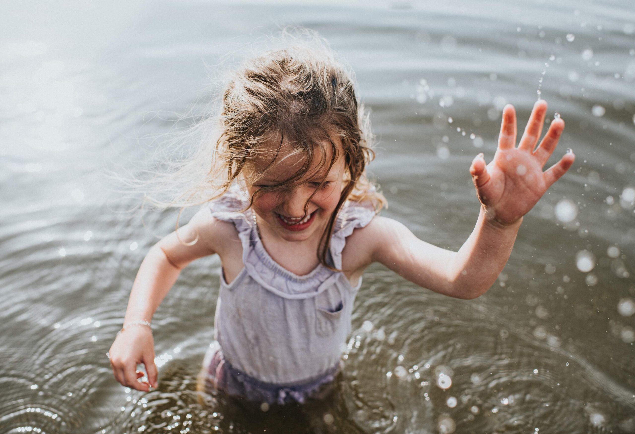 A little girl splashing around as she plays in the water.