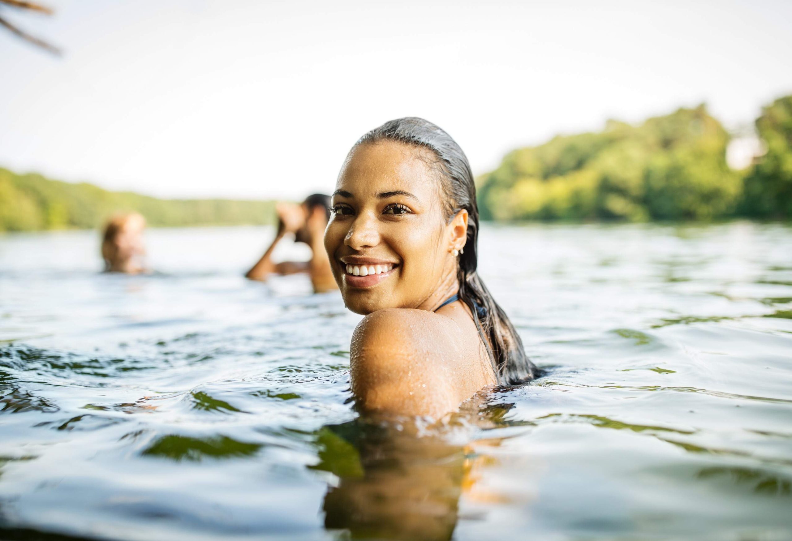 A beautiful woman swimming in the sea with friends.