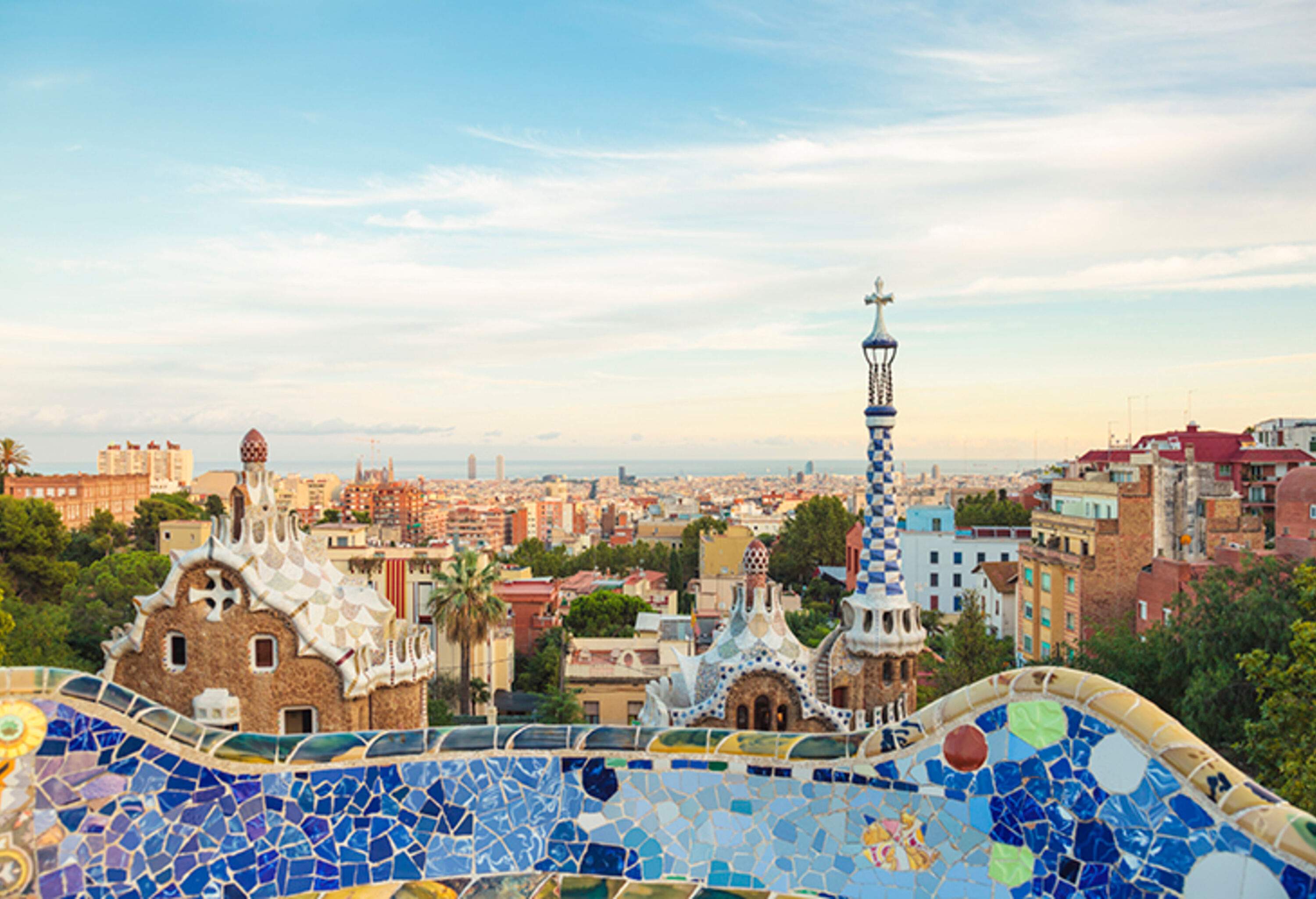 A balcony with colourful mosaics of ceramic tiles and views of the city's metropolitan surroundings.
