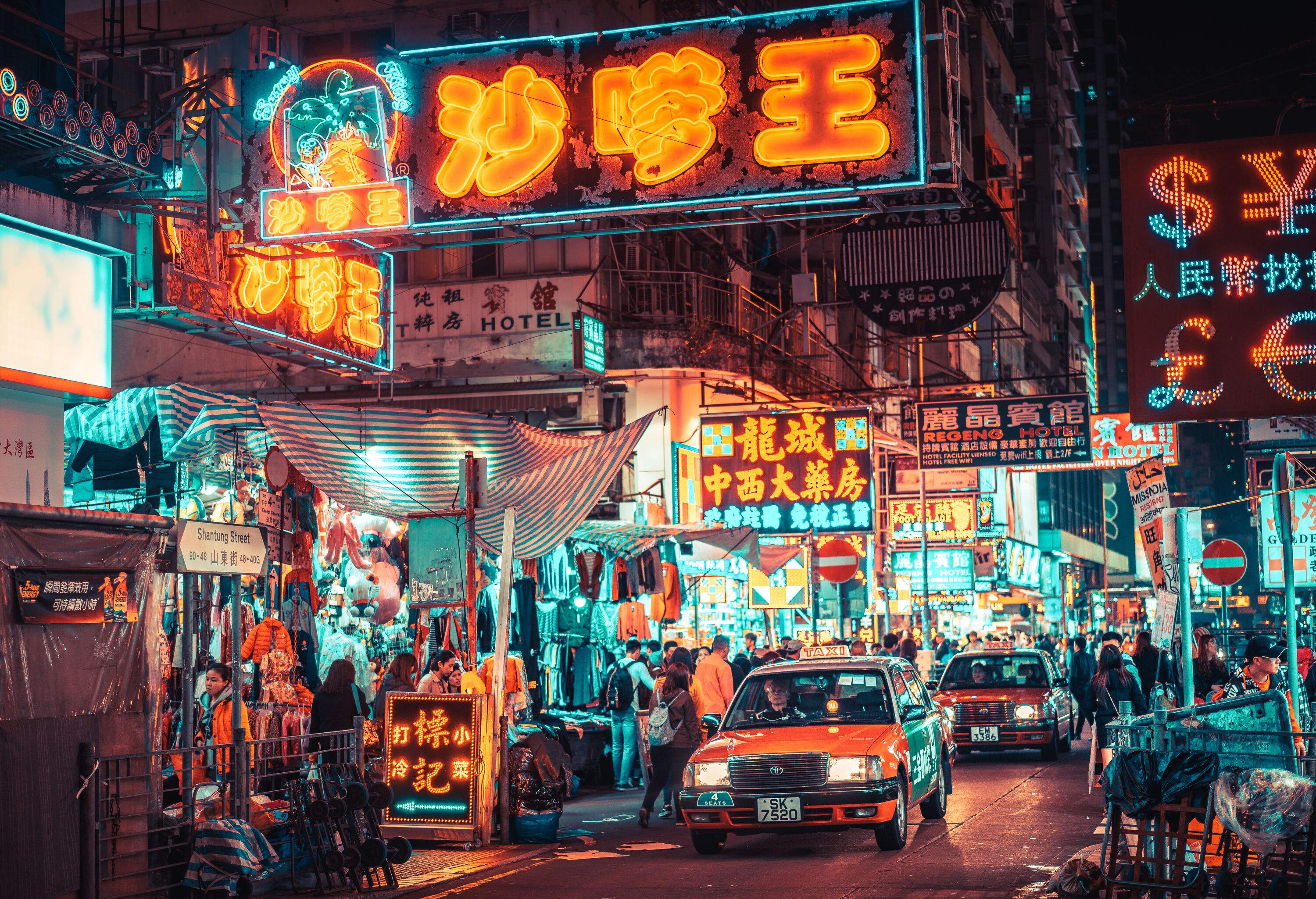 Signages illuminated in neon colours lit the bustling street lined with boutique shops at night. 