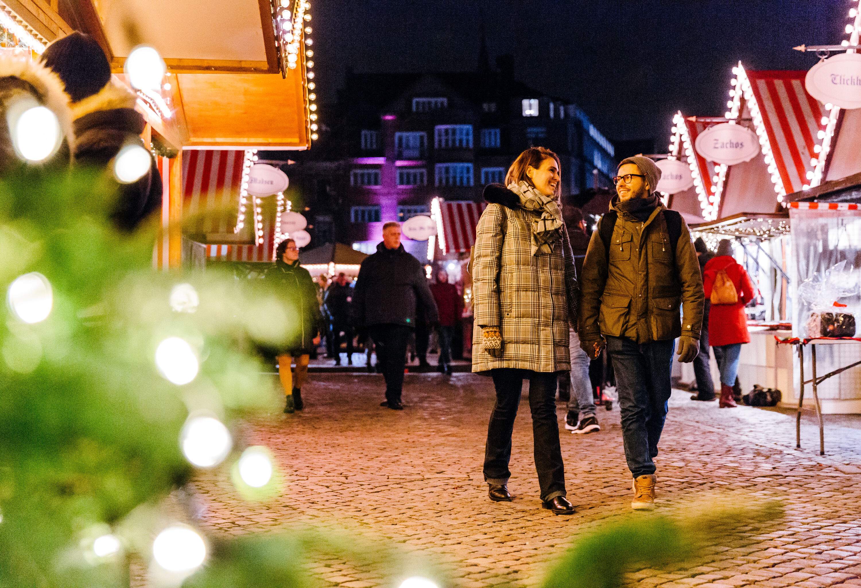 Couple walking hand in hand through a Christmas market in the evening