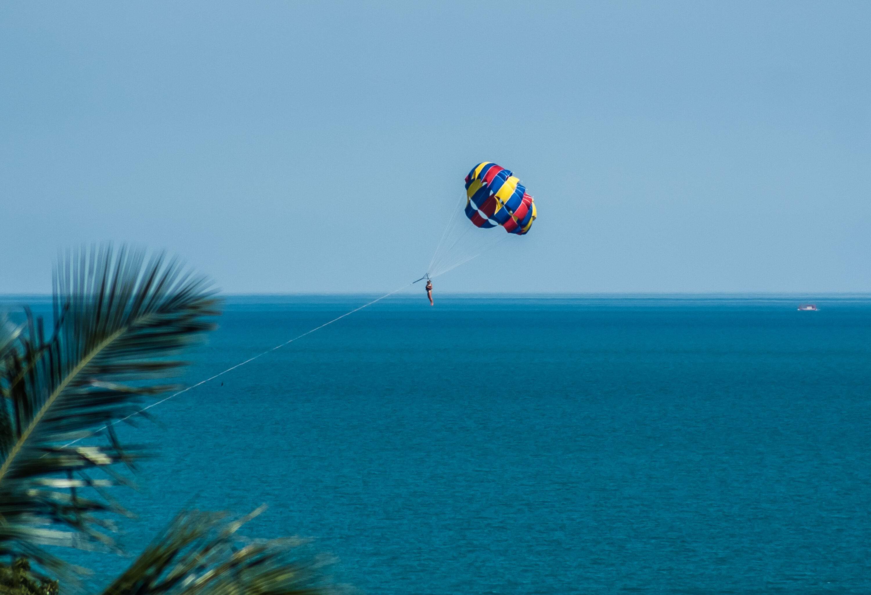 An individual in a colourful parasail over the tranquil blue sea.