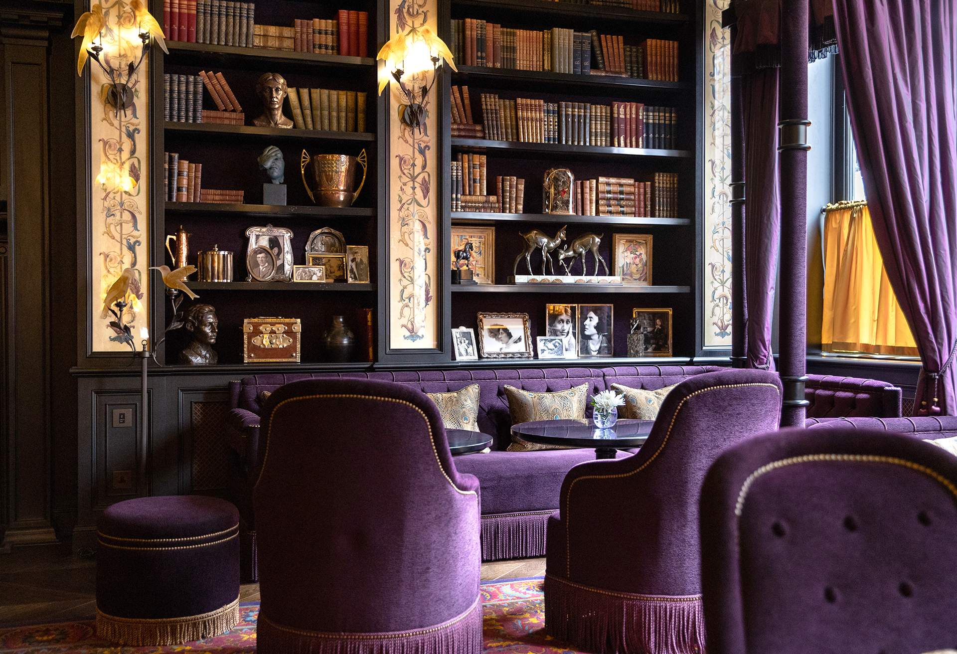 Interior sitting rooom decked in luxurious purple velvet with library in the background