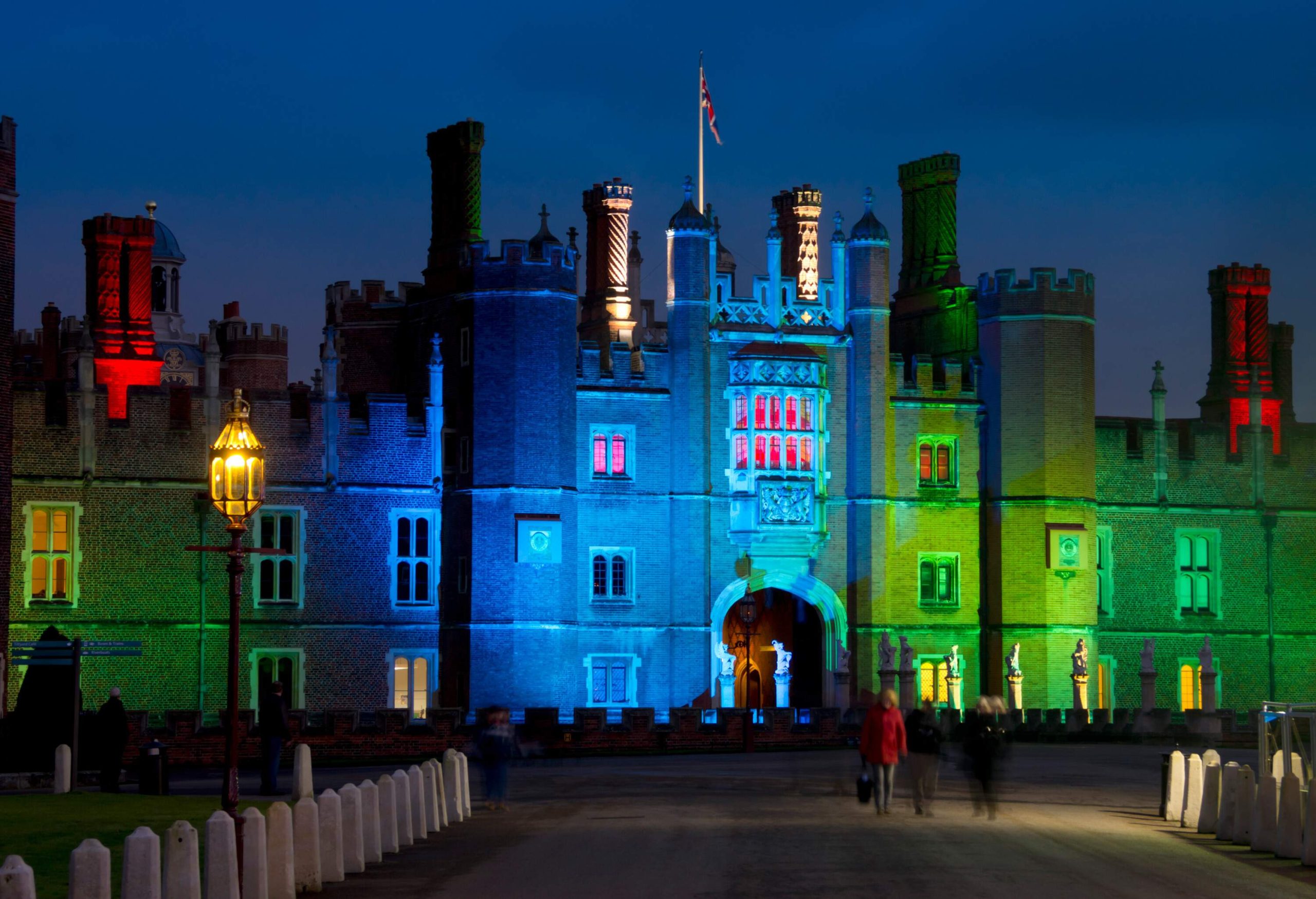 The facade of a royal palace is illuminated with different colours at night.