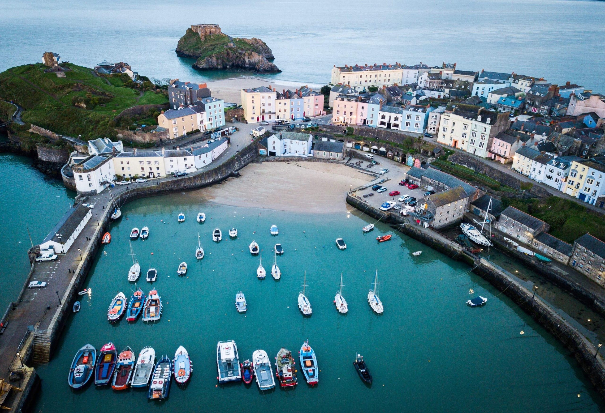 Aerial view of a harbour surrounded by classic, traditional and colourful buildings with a small rocky island nearby.