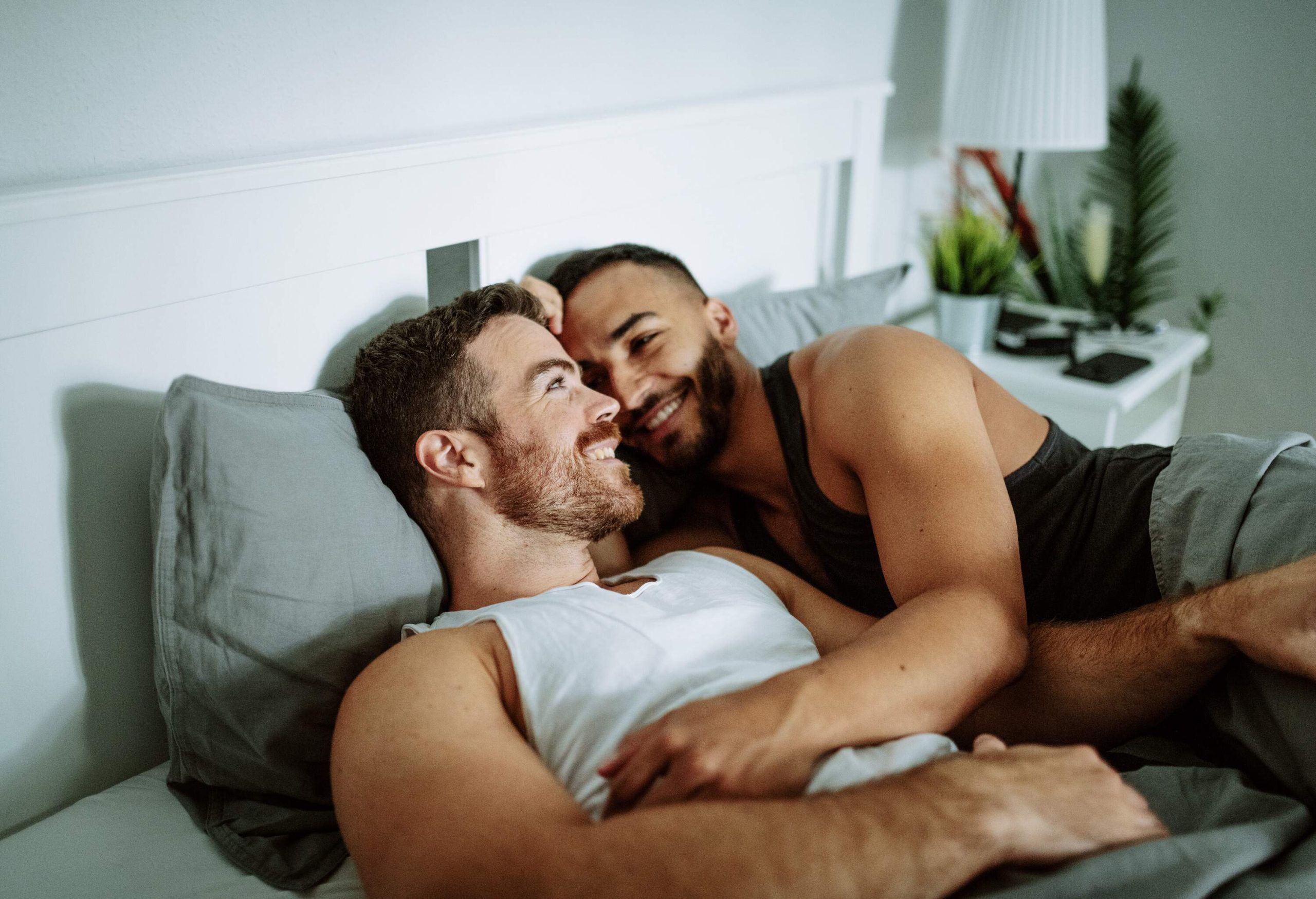 Happy gay couple lying in bed.