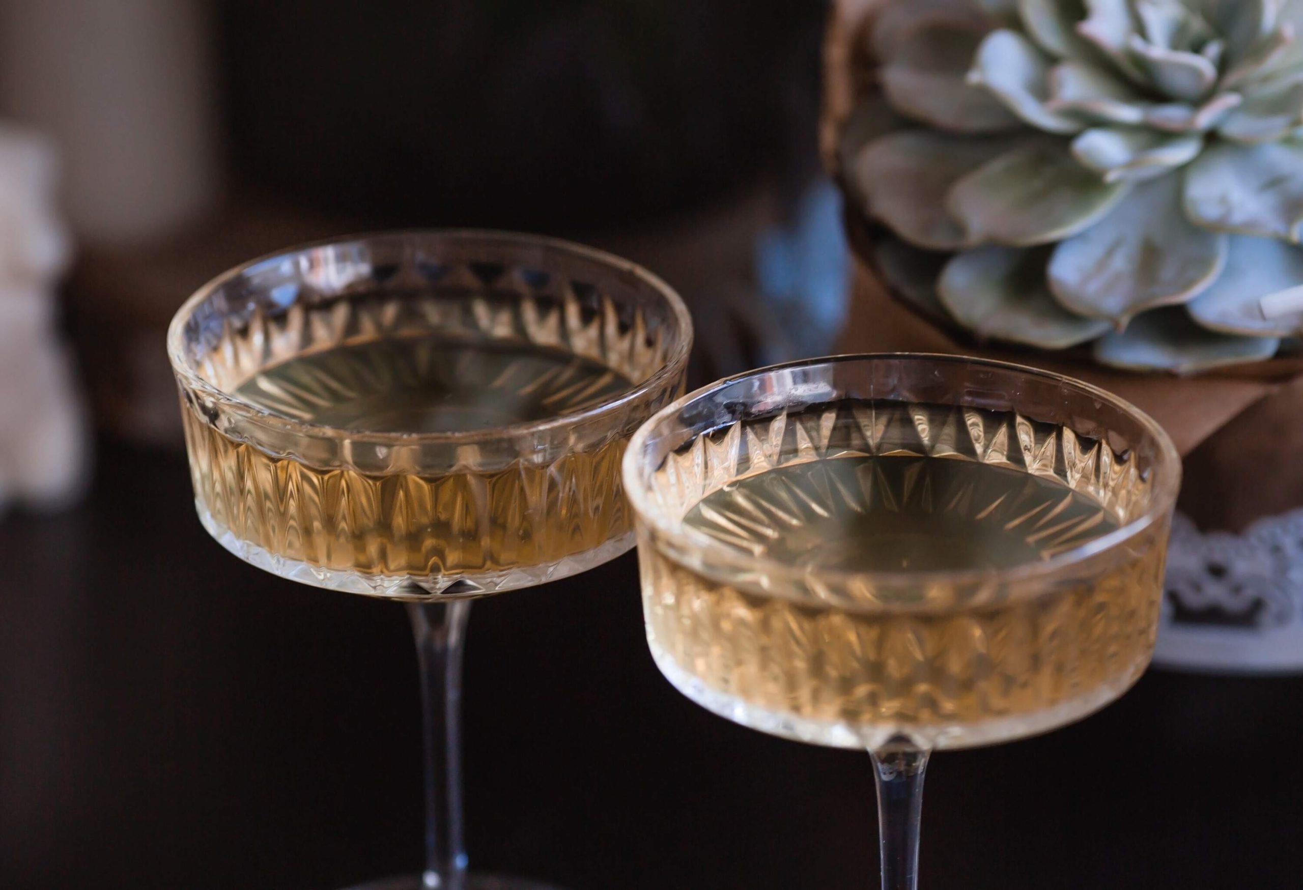 A pair of champagne glasses sitting on a table next to a beautiful centerpiece.