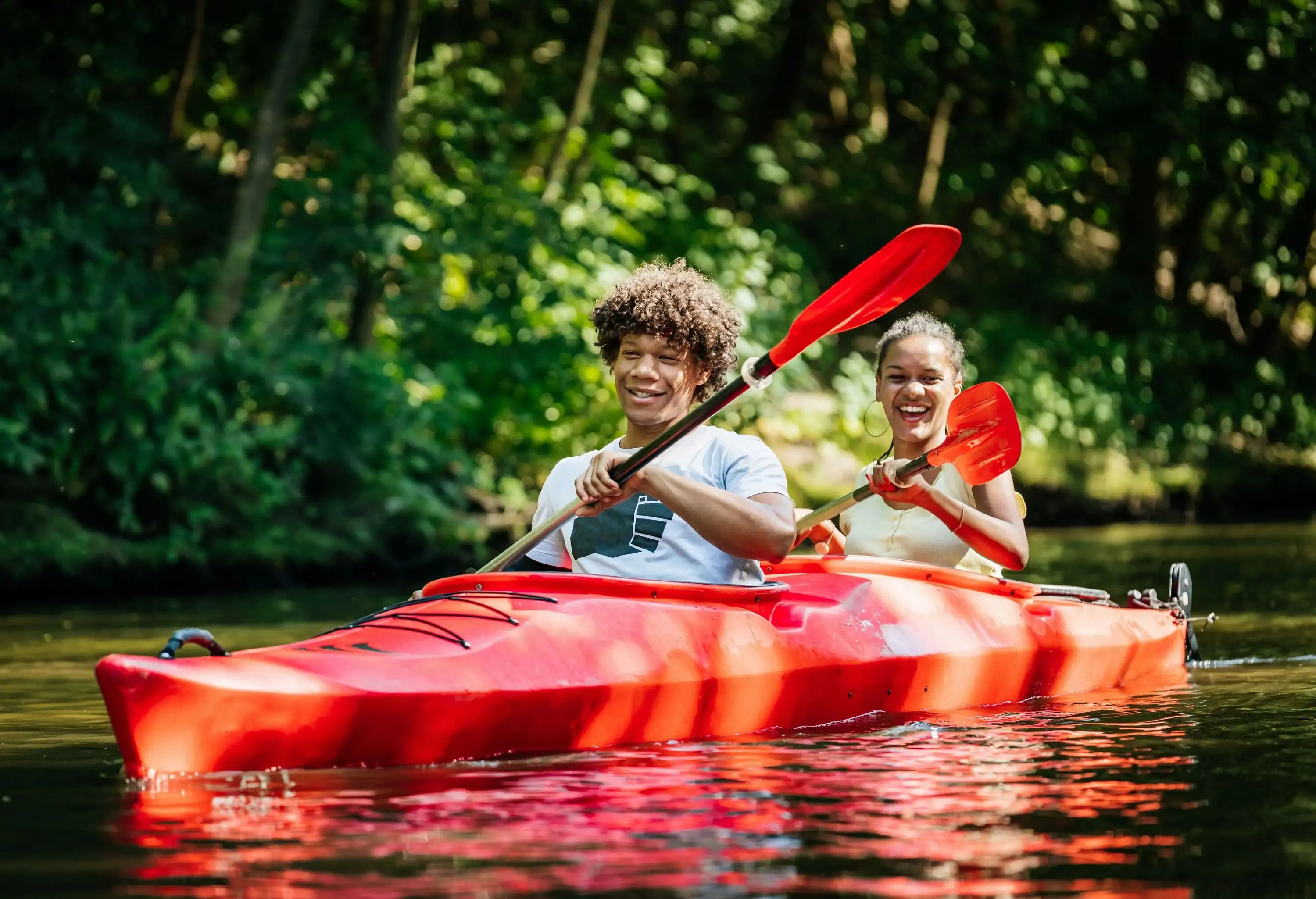 A happy couple takes in the scenery and the river on a kayaking trip.