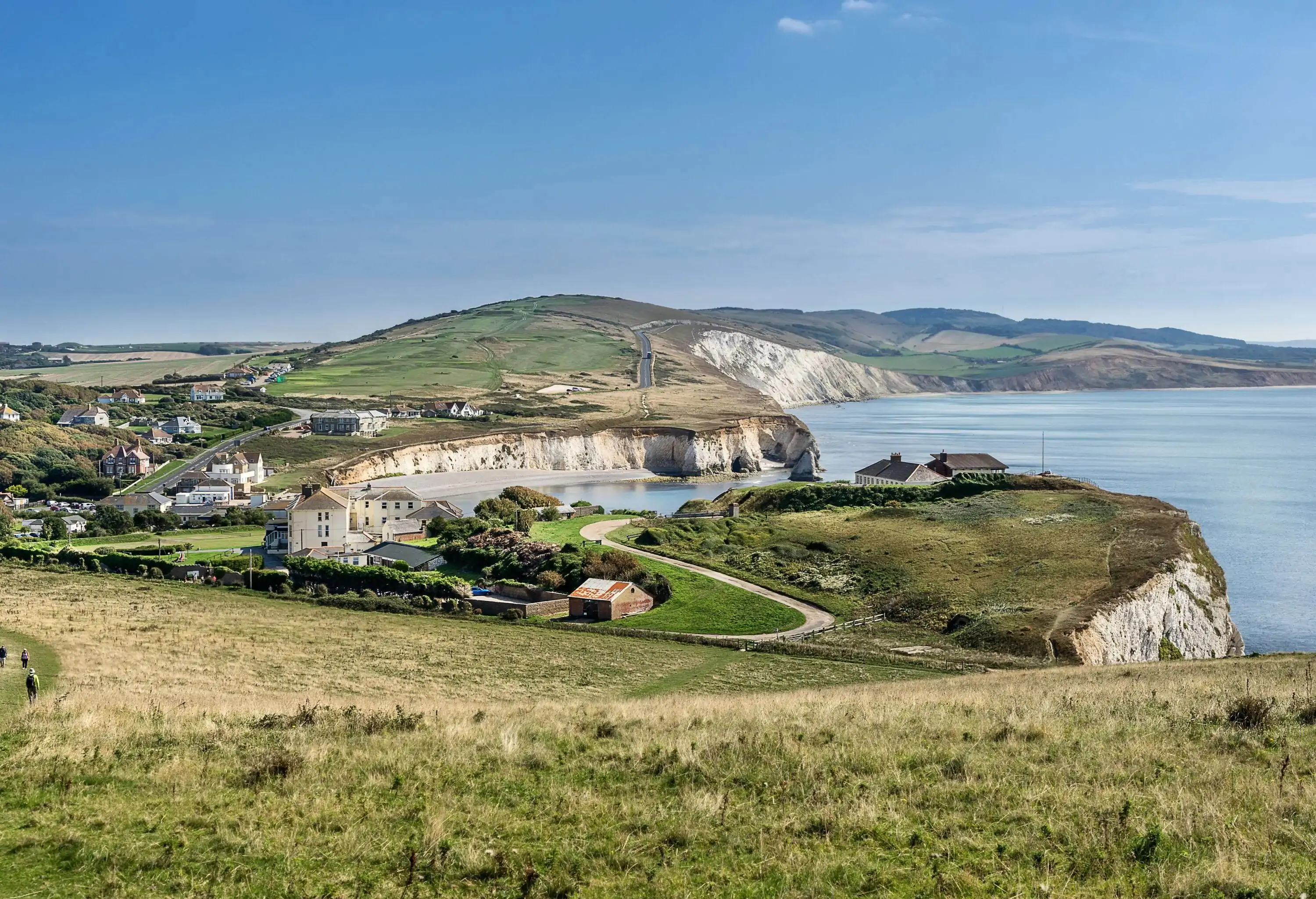 A coastal village perched on top of the grassy cliffs surrounding the bay.
