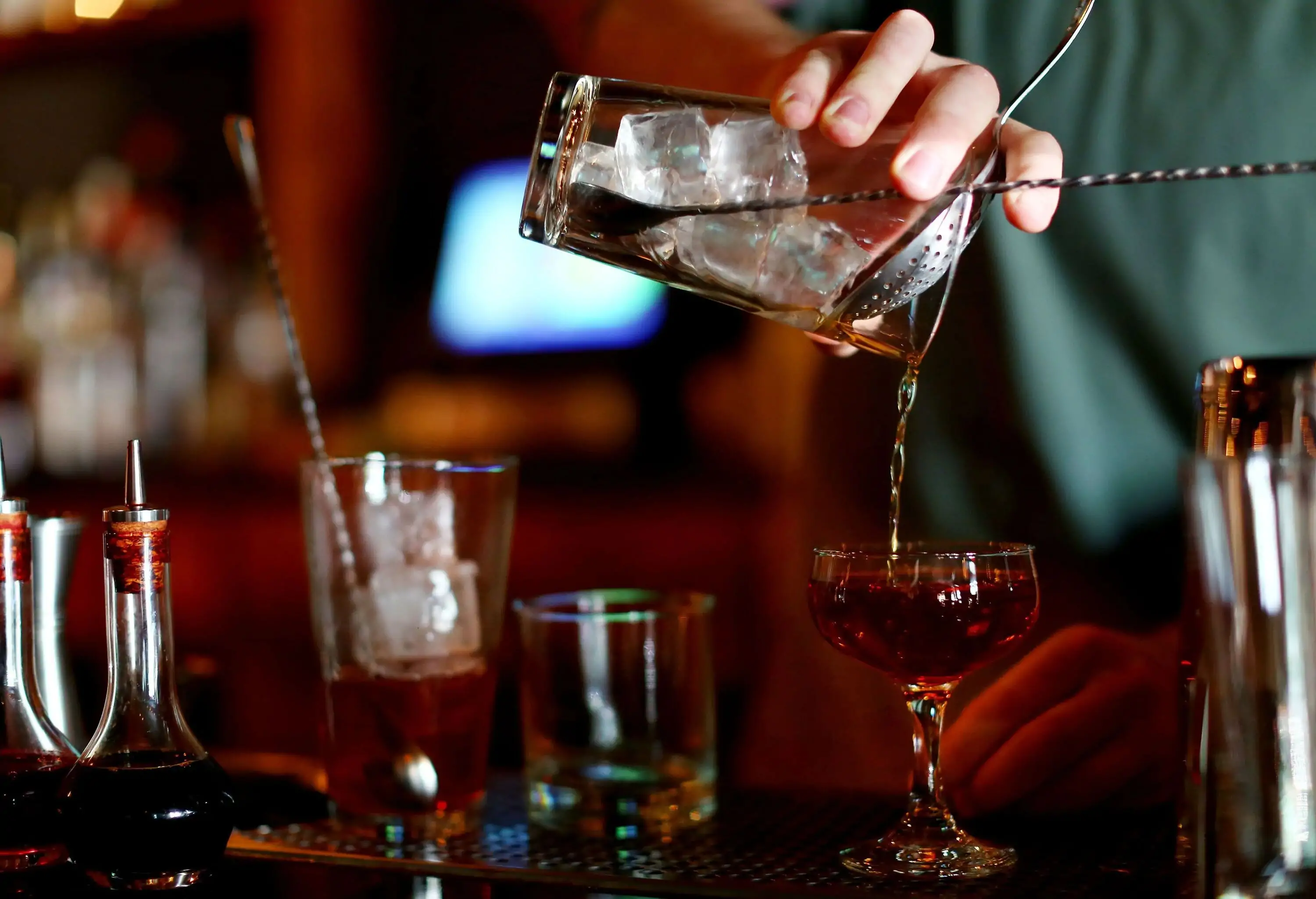A bartender prepares a whisky drink at the bar counter.