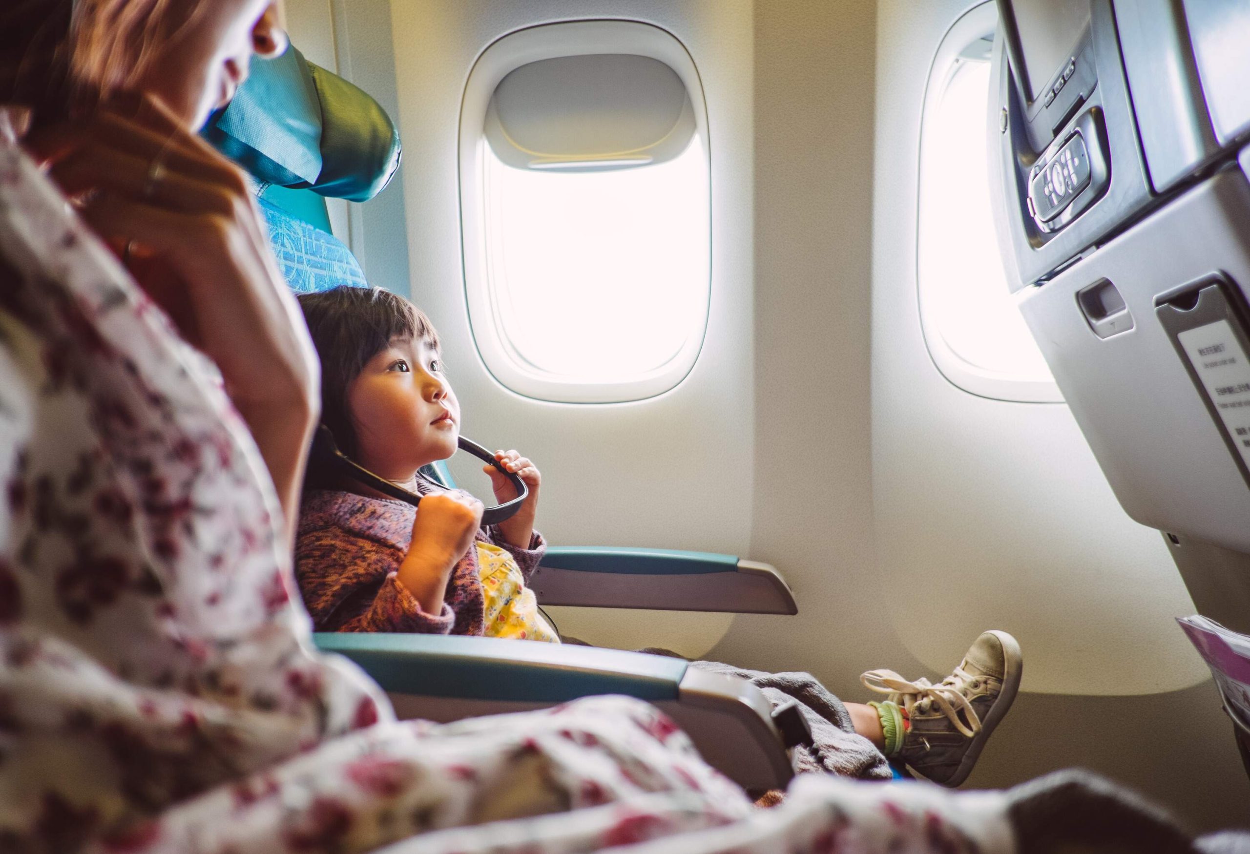 A little girl sitting next to her mother watching PTV on an airplane.