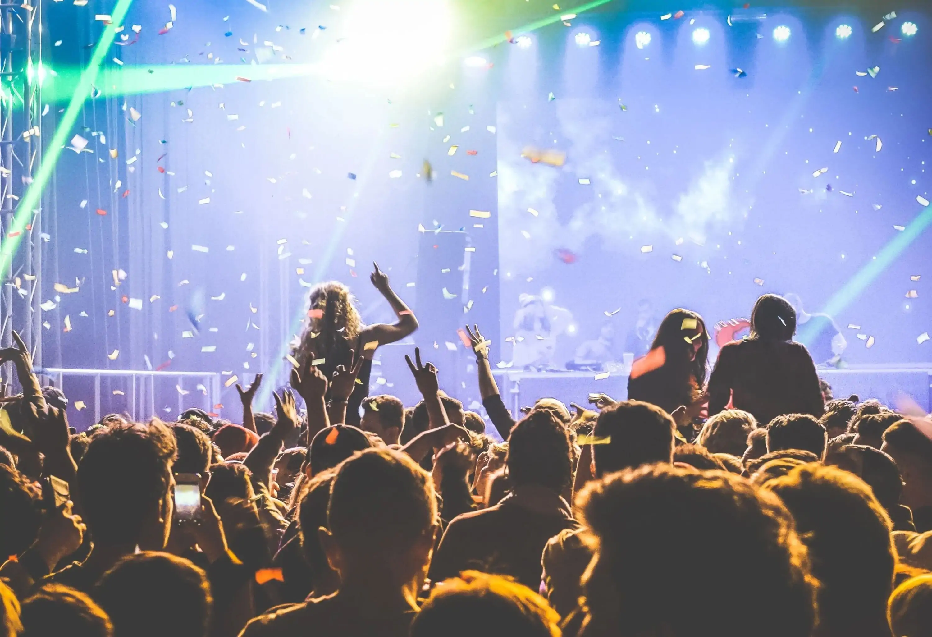 A lively concert party with an enthusiastic audience enjoying the music as colourful confetti falls from above.