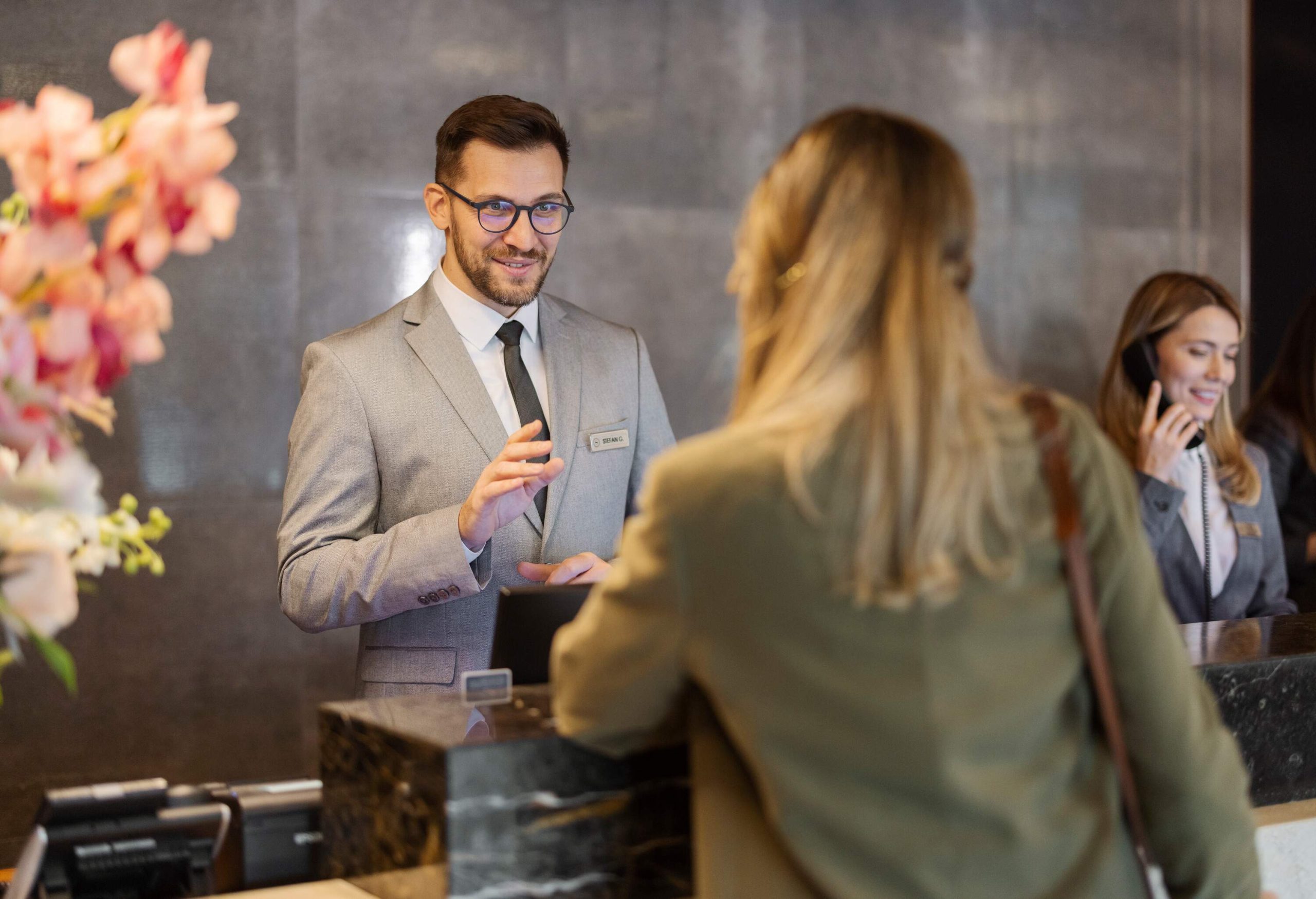 Male receptionist at front office talking with guest in hotel.