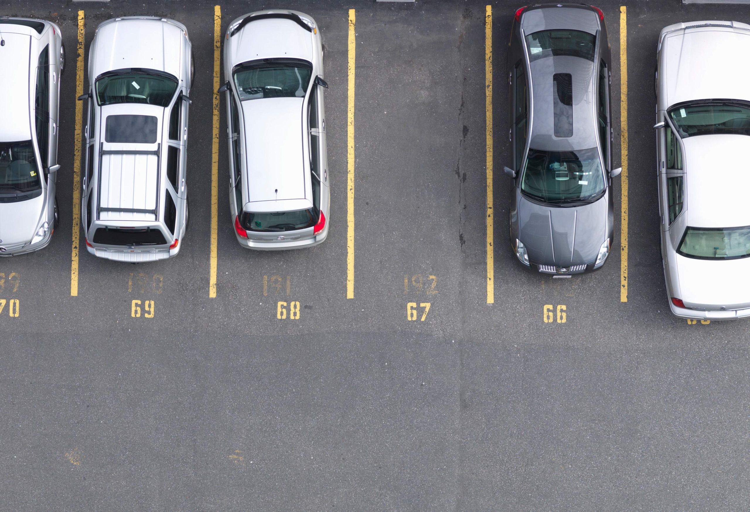 Cars parked in numbered parking spaces with one vacant spot.
