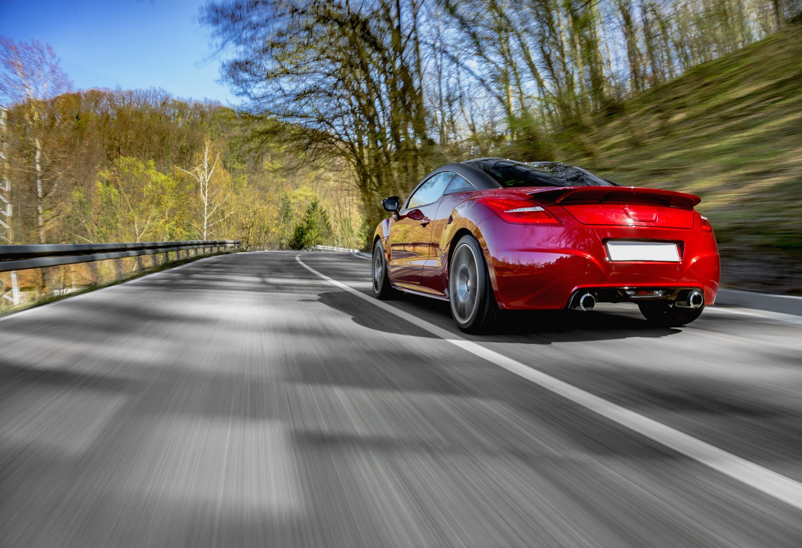 A vibrant red sports car speeding down the open road, exuding power and excitement with its sleek design and thrilling performance.