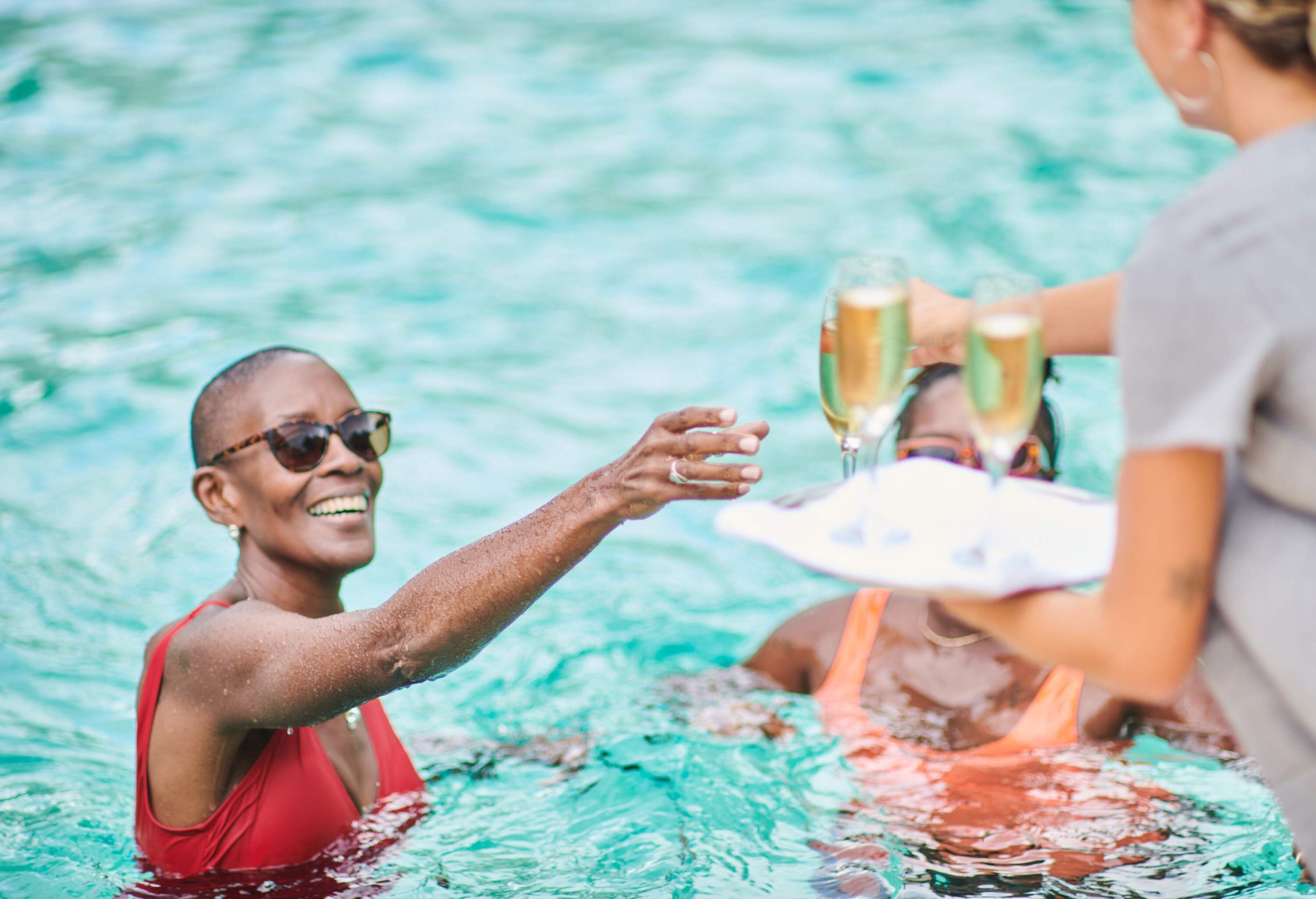 Taking glasses of champagne to her clients at the swimming pool of a luxury private villa.