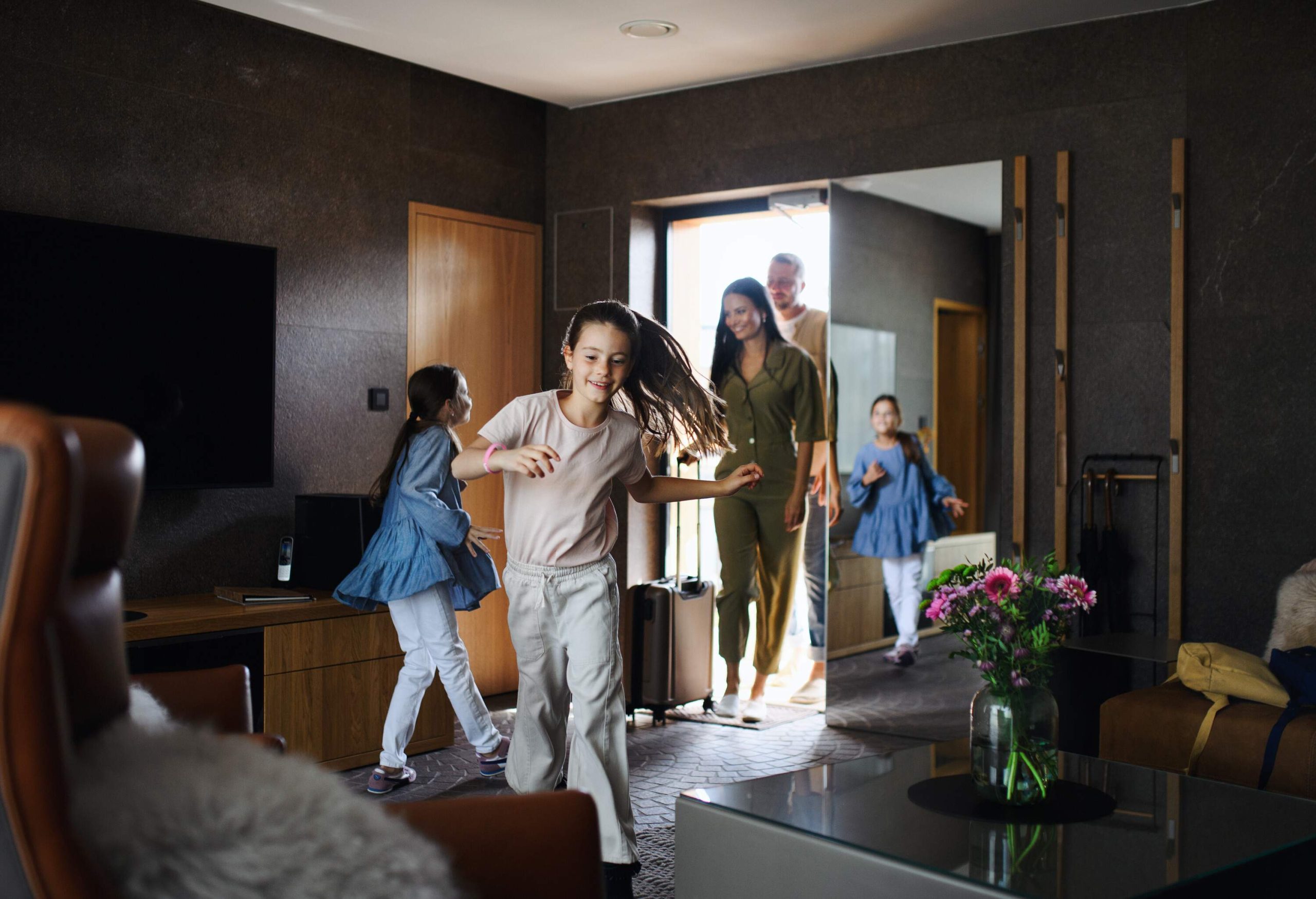 A happy young family with two children enetring room at luxury hotel, summer holiday.