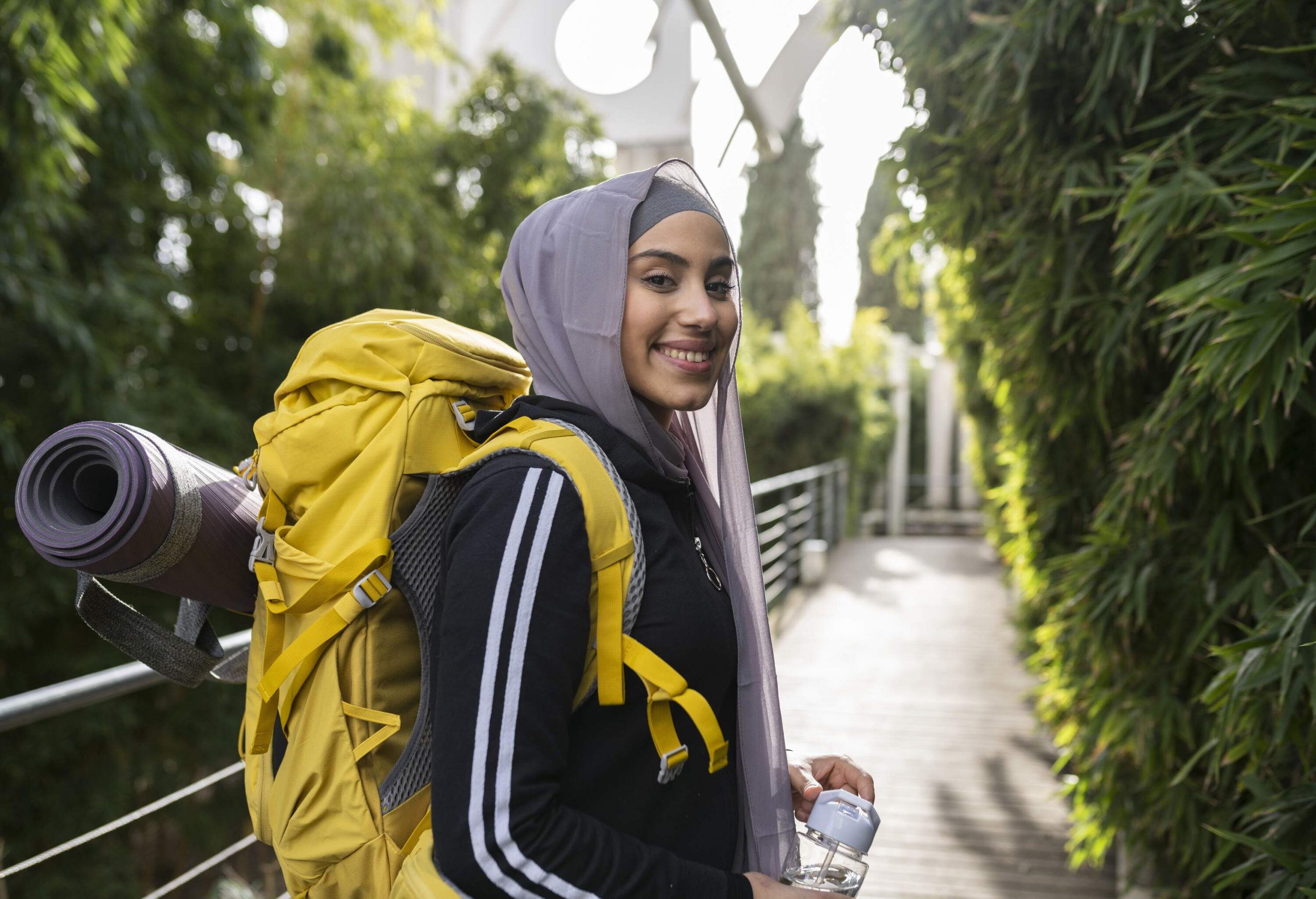 Portrait of a young backpacker wearing a hijab and smiling at the camera on vacation