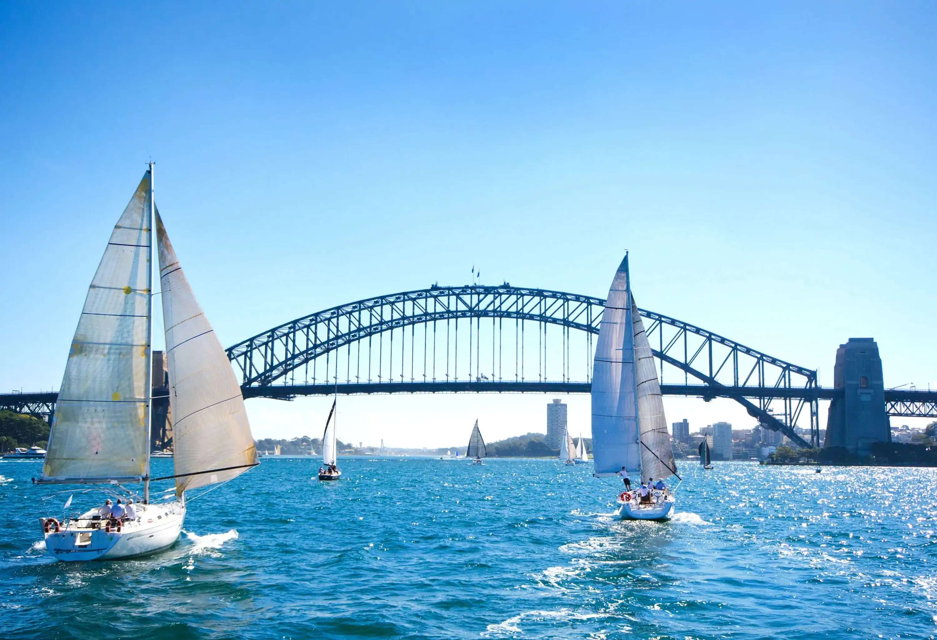 A bridge across a harbour filled with cruising sailboats.