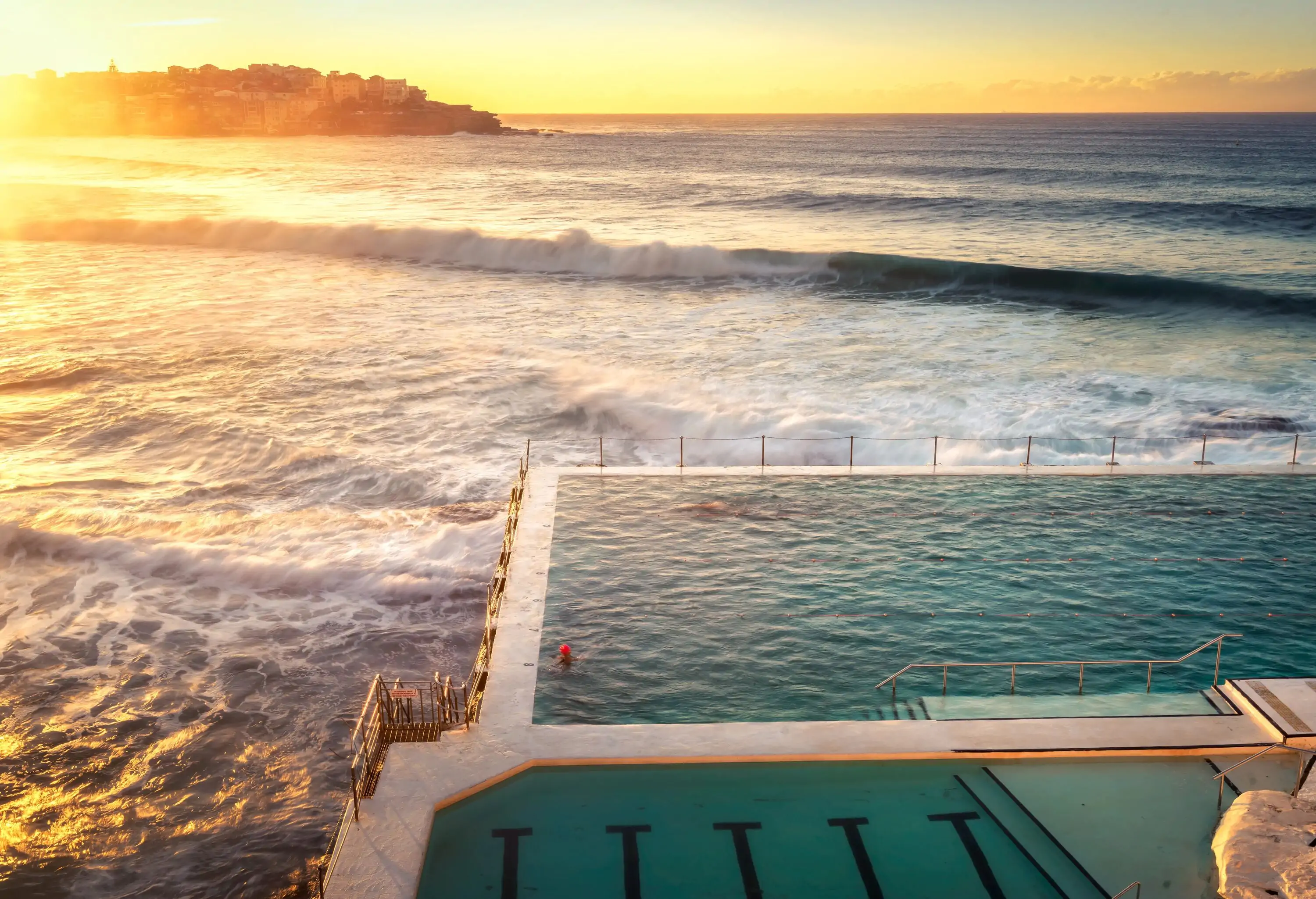 The iconic Bondi Beach, with its rolling waves, is beautifully complemented by a crystal-clear swimming pool nestled along the shore.
